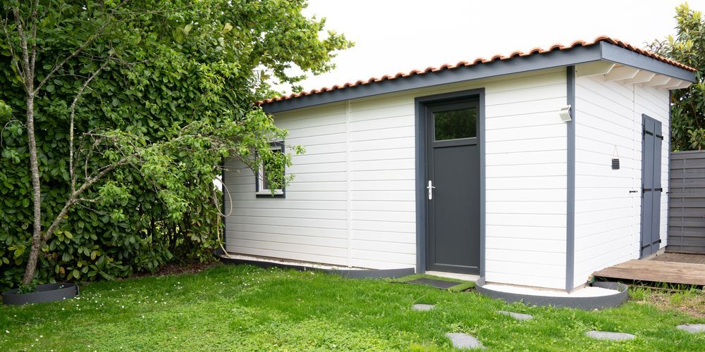 A Small White House With a Black Door is Sitting — Shane Rice Builder & Renovation Specialist In Southside, QLD