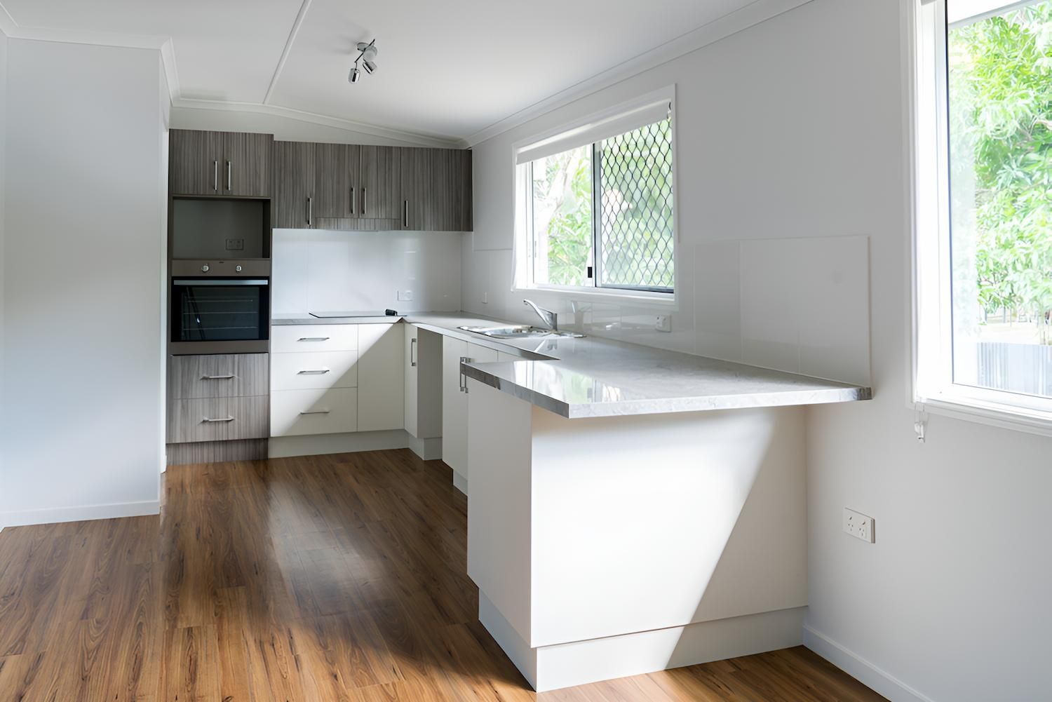 An Empty Kitchen With Wooden Floors — Shane Rice Builder & Renovation Specialist In Southside, QLD