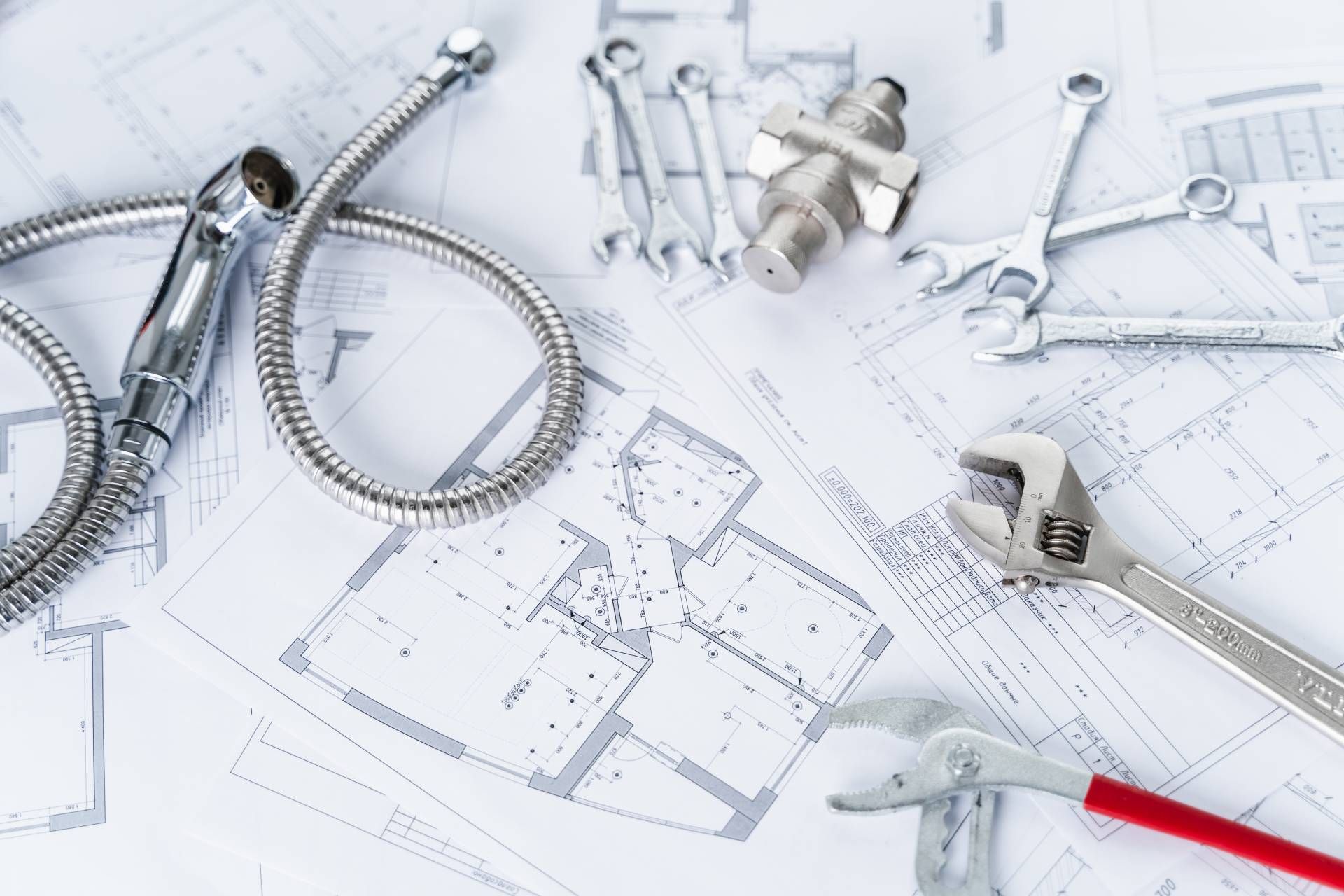A bunch of plumbing tools are sitting on top of a blueprint.