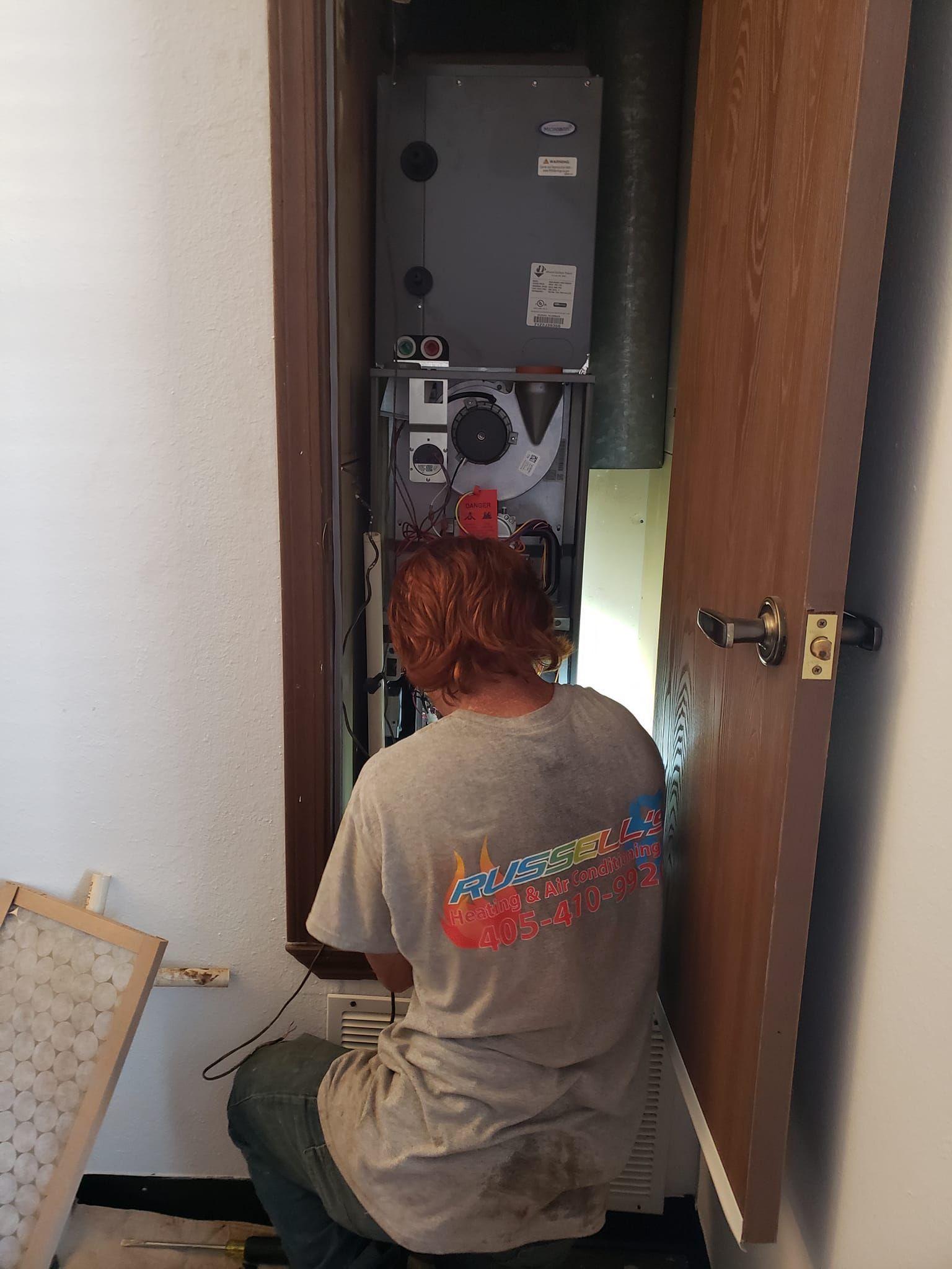 A man is working on an air conditioner in a closet.