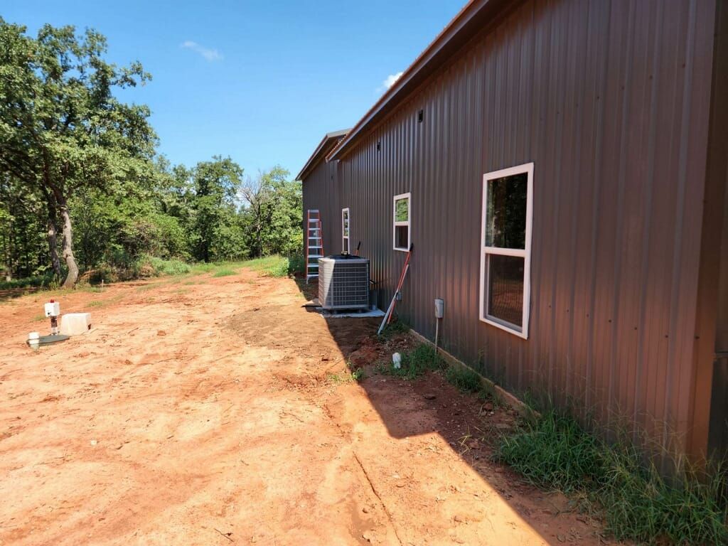 A brown building with a lot of windows is sitting in the middle of a dirt field.