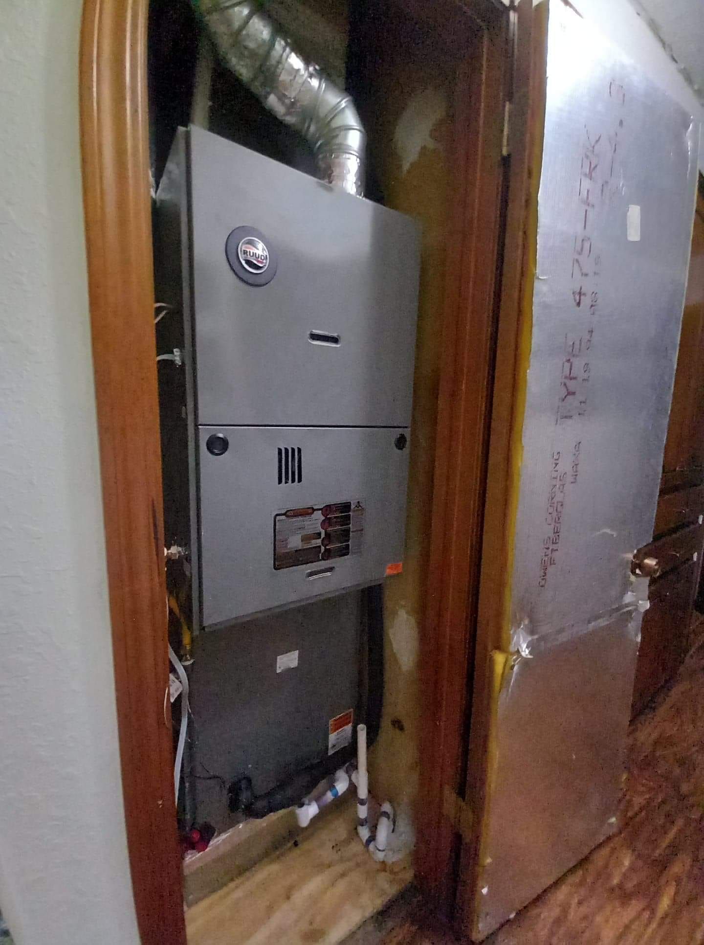 An air conditioner is sitting in a closet next to a door.