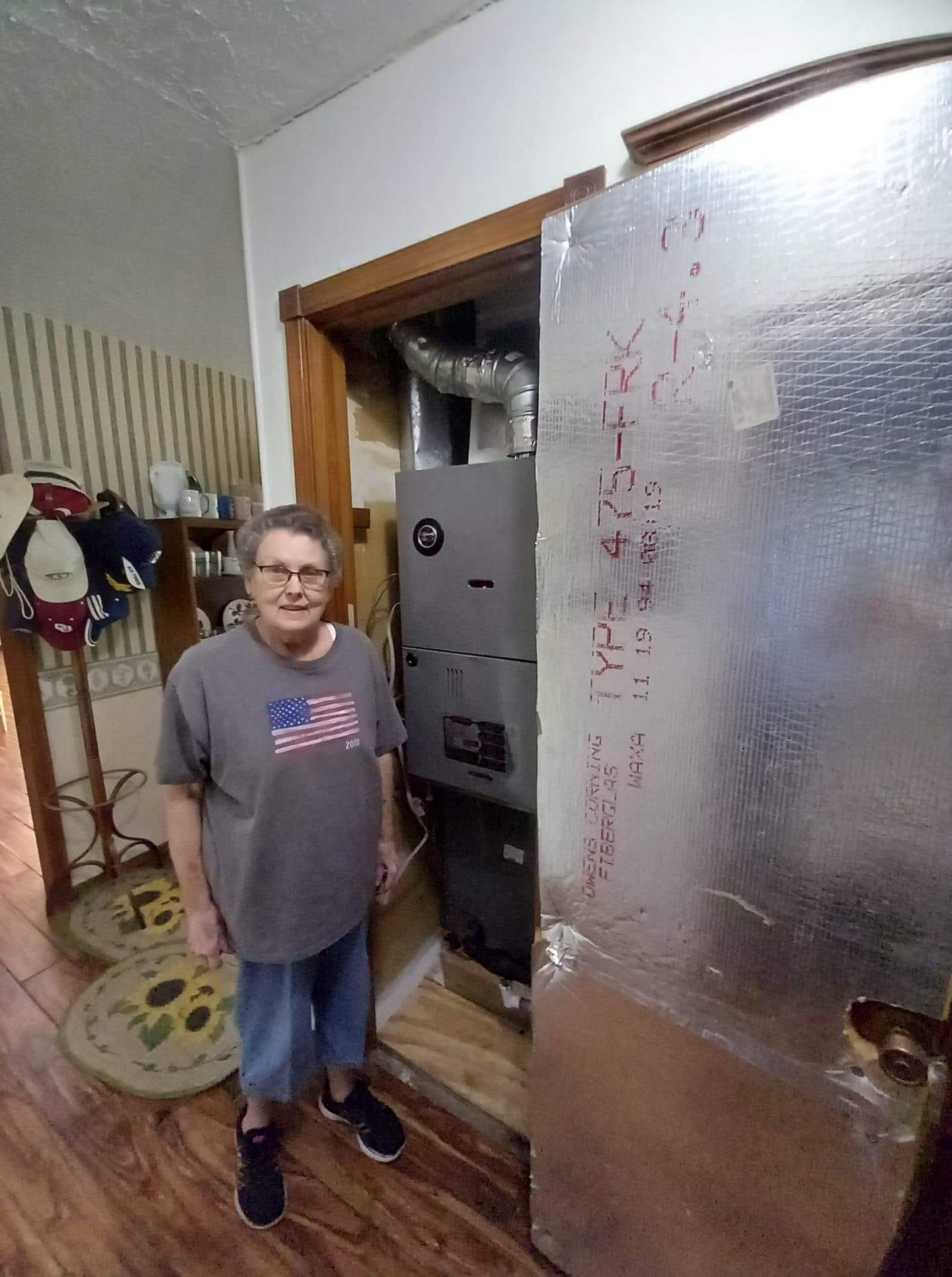 A woman is standing in front of a heater in a room.