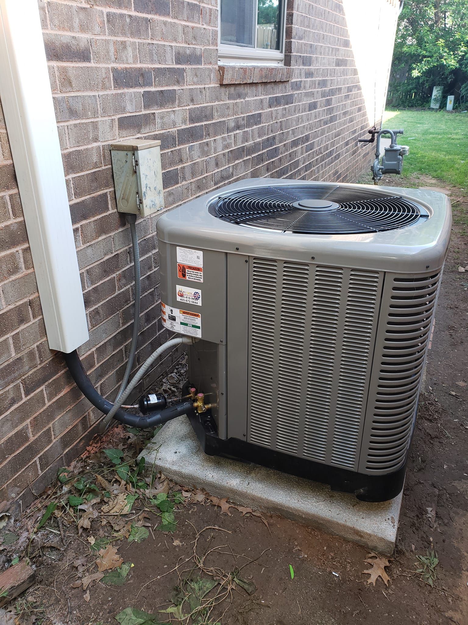 An air conditioner is sitting on the side of a brick building.