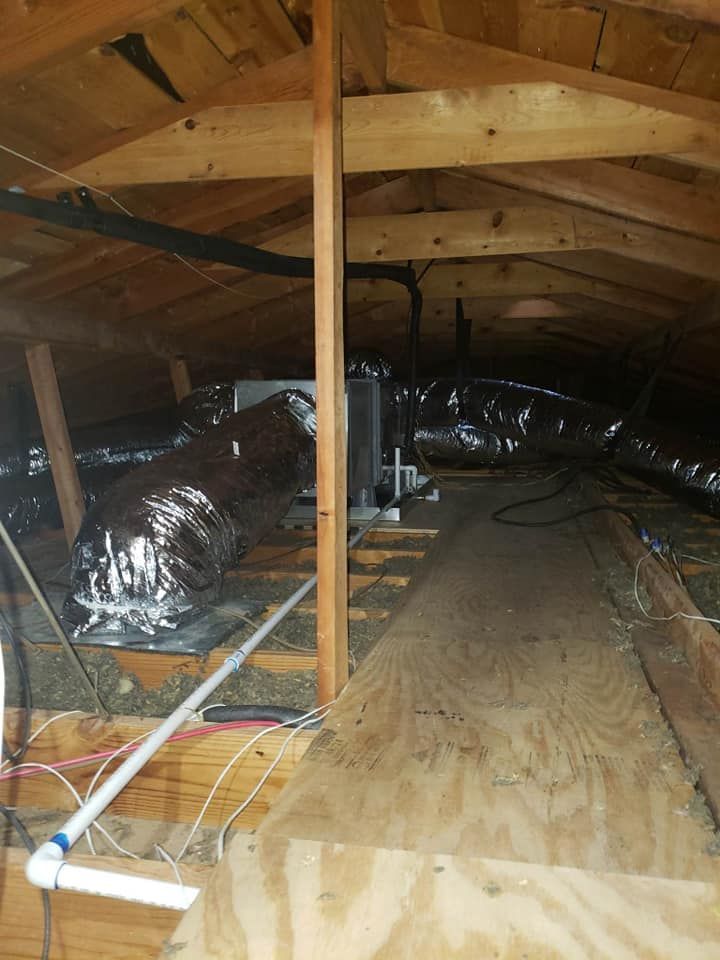 An attic with a lot of pipes and wires coming out of it.
