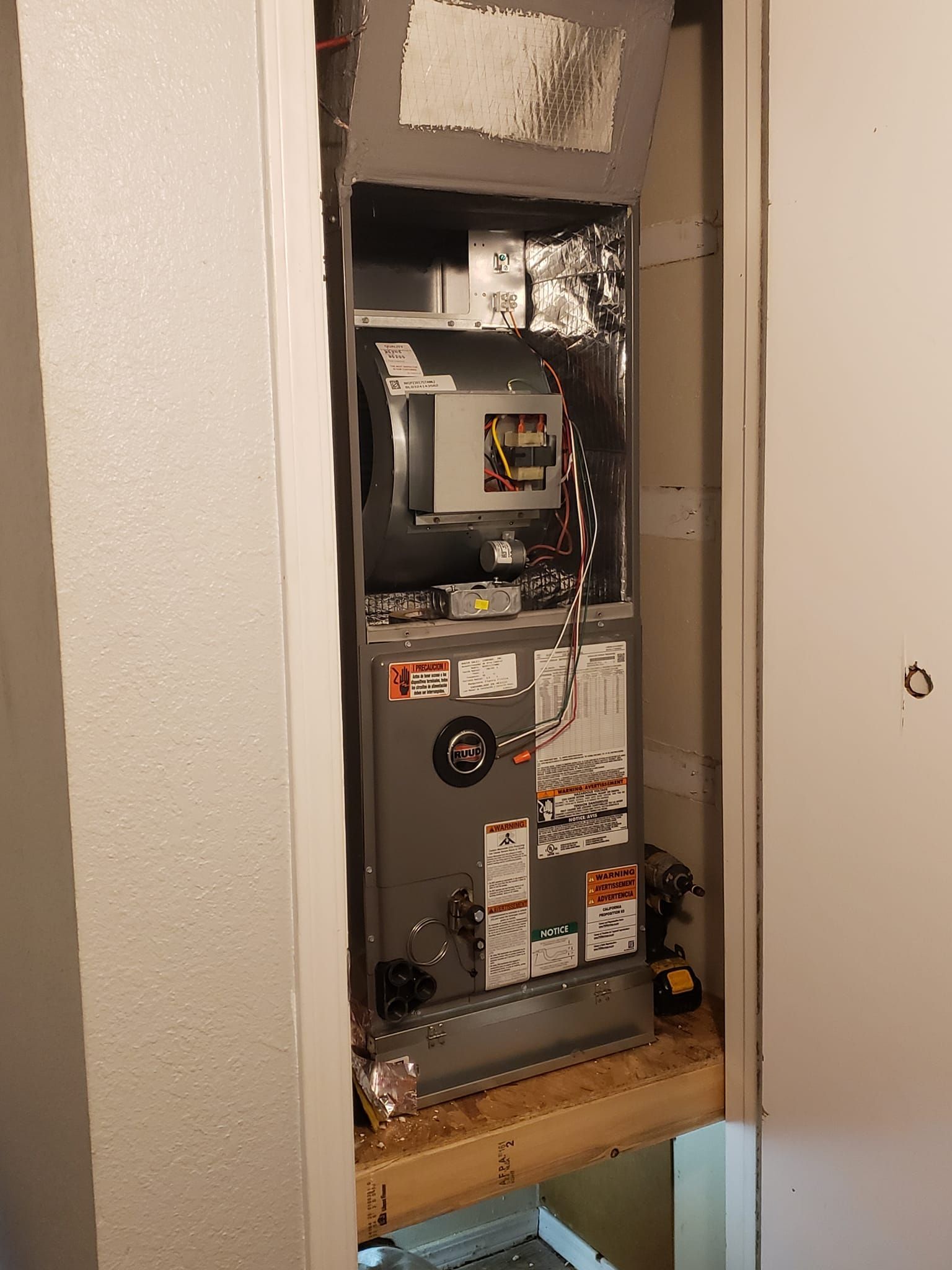 A furnace is sitting in a closet next to a door.