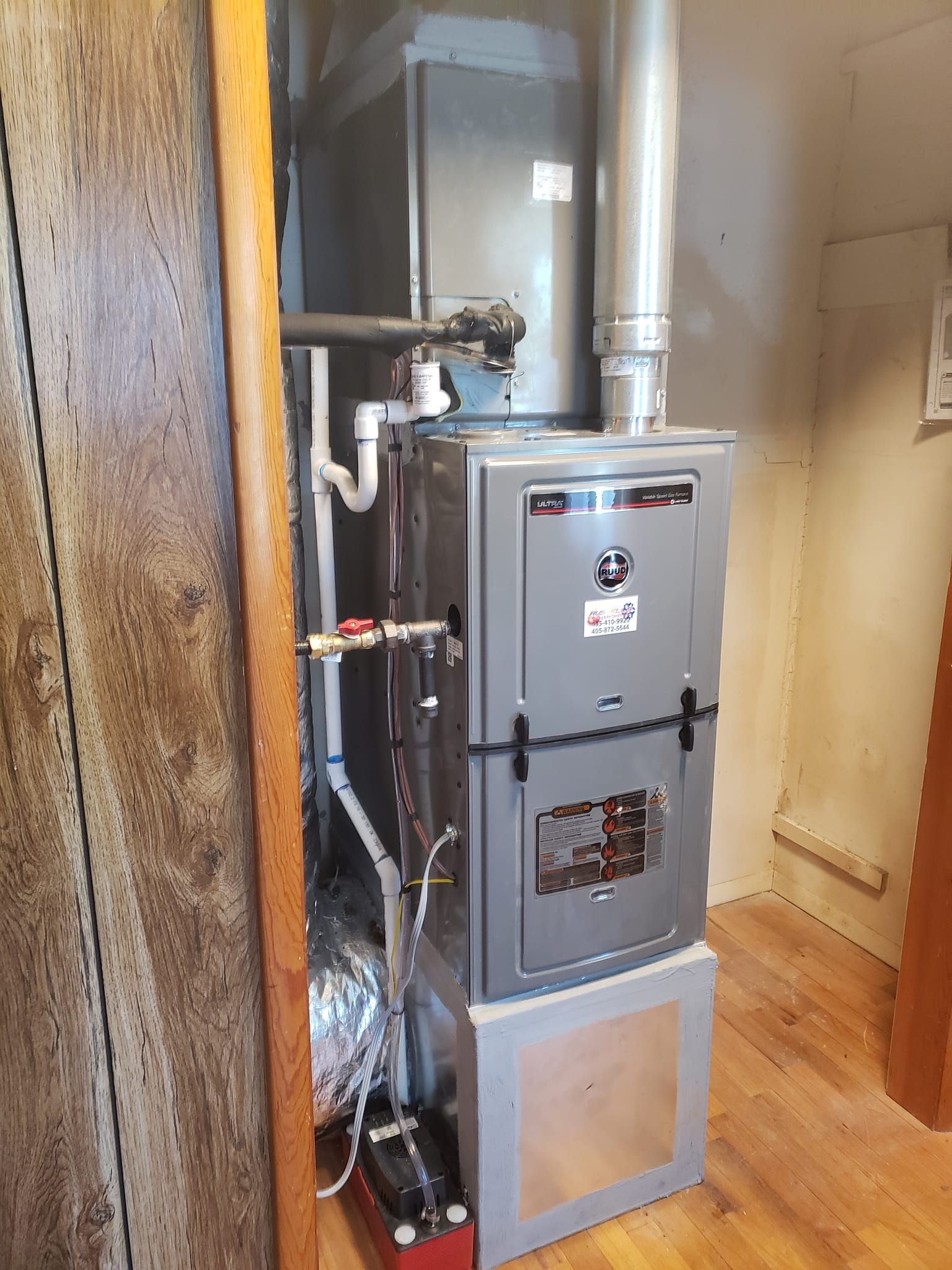A furnace is sitting in a room next to a wooden wall.