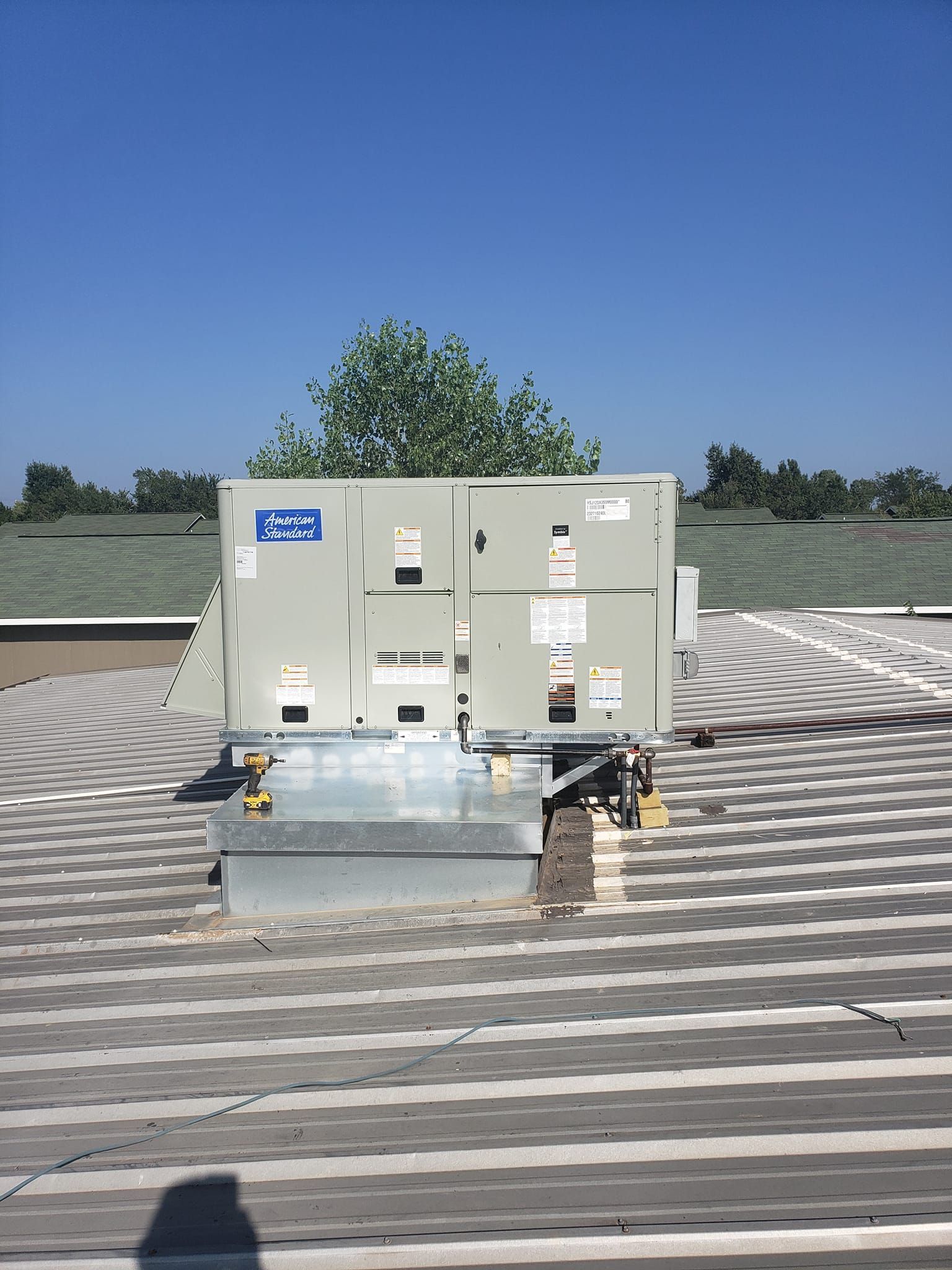 An air conditioner is sitting on top of a striped roof.