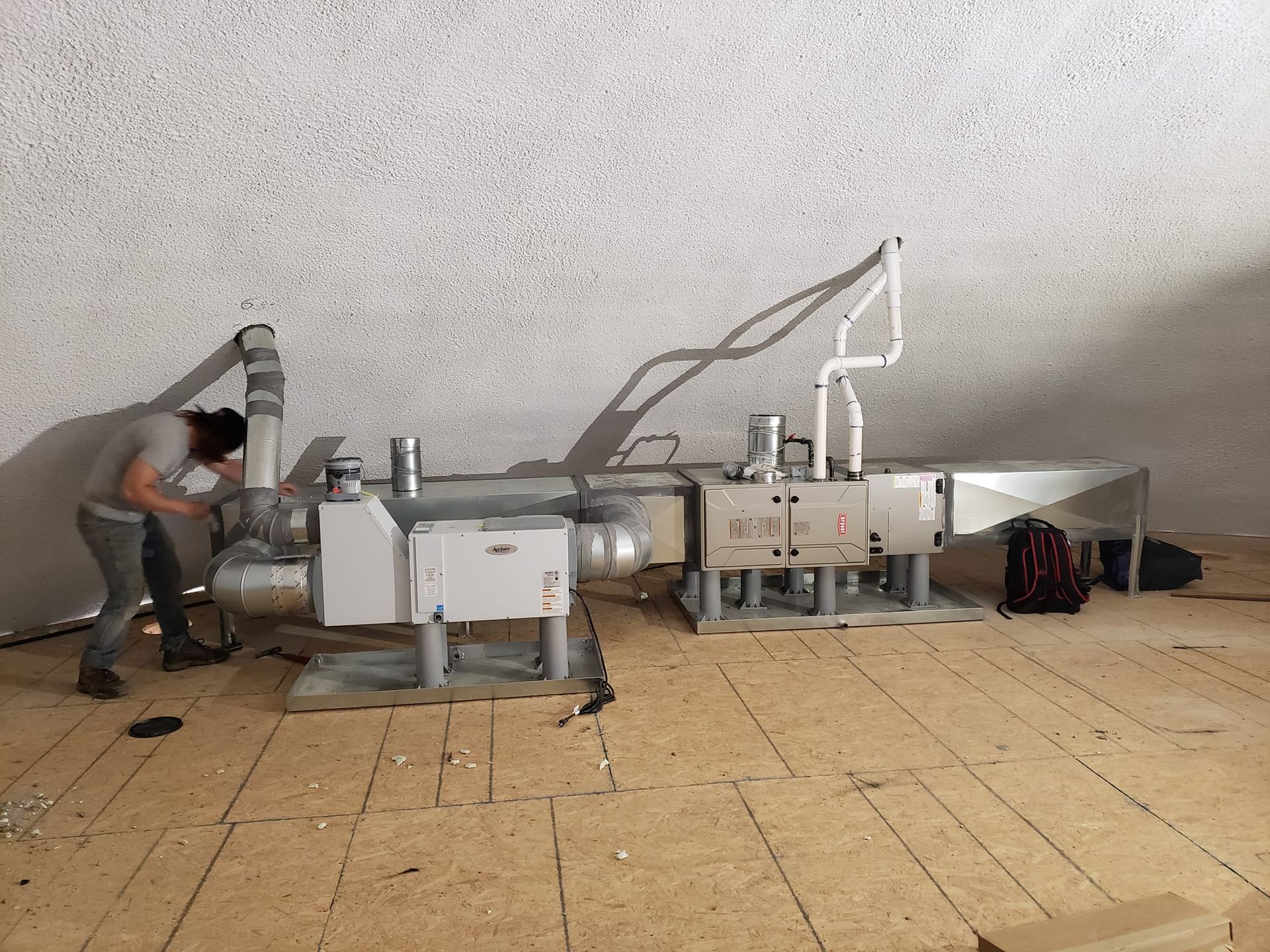 A man is working on a ventilation system in a room.