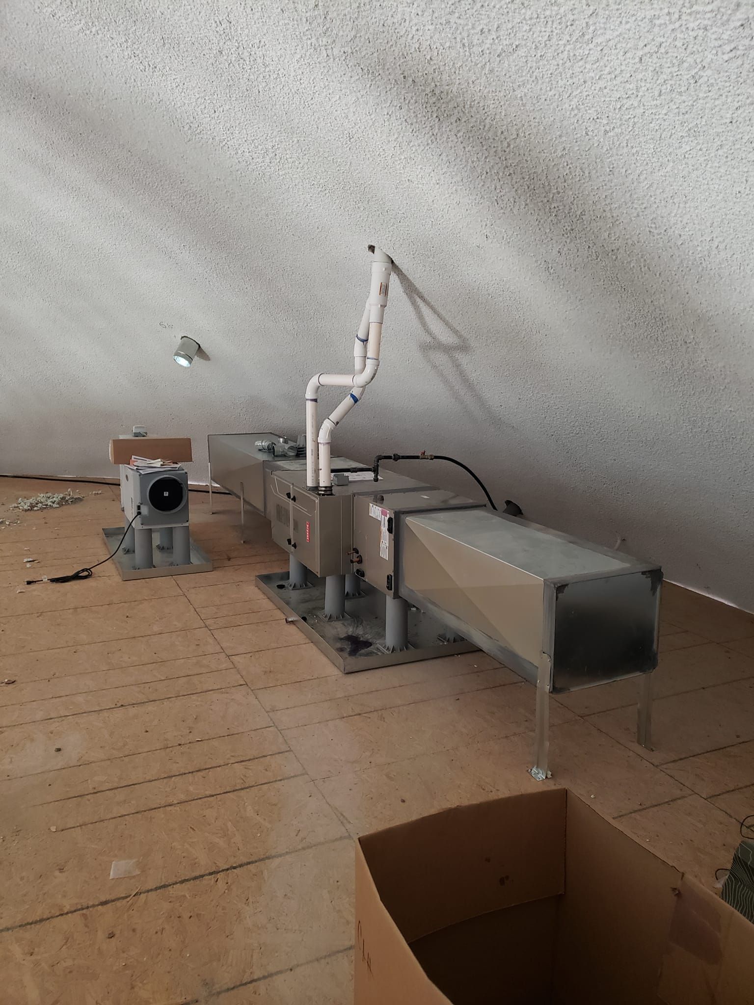 A room with a lot of pipes and a box on the floor.