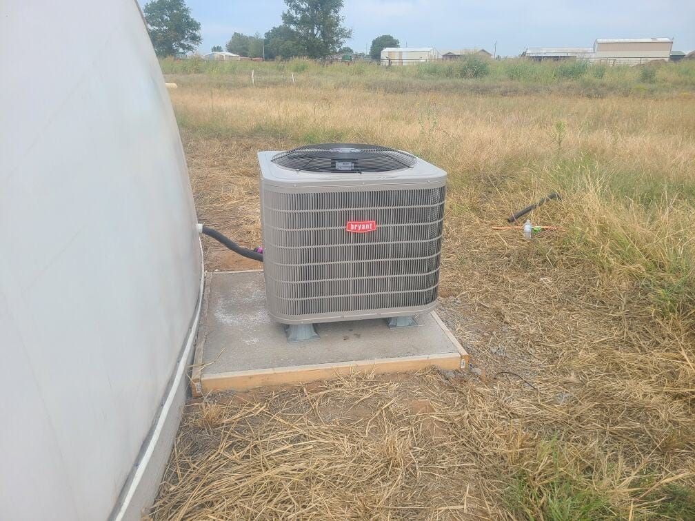 A large air conditioner is sitting in the middle of a field.