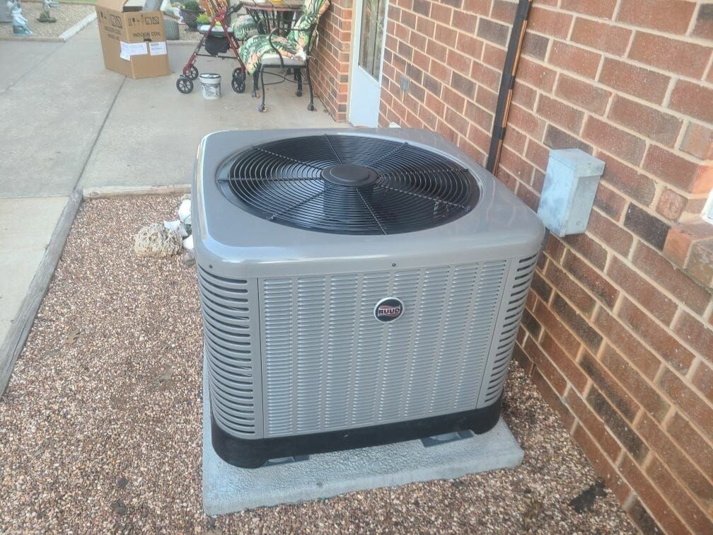 An air conditioner is sitting on the side of a brick building.