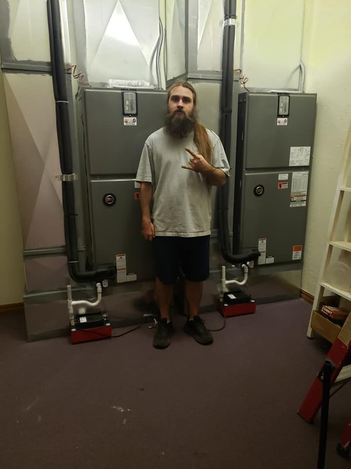 A man with a beard is standing in a room with a lot of air conditioners.