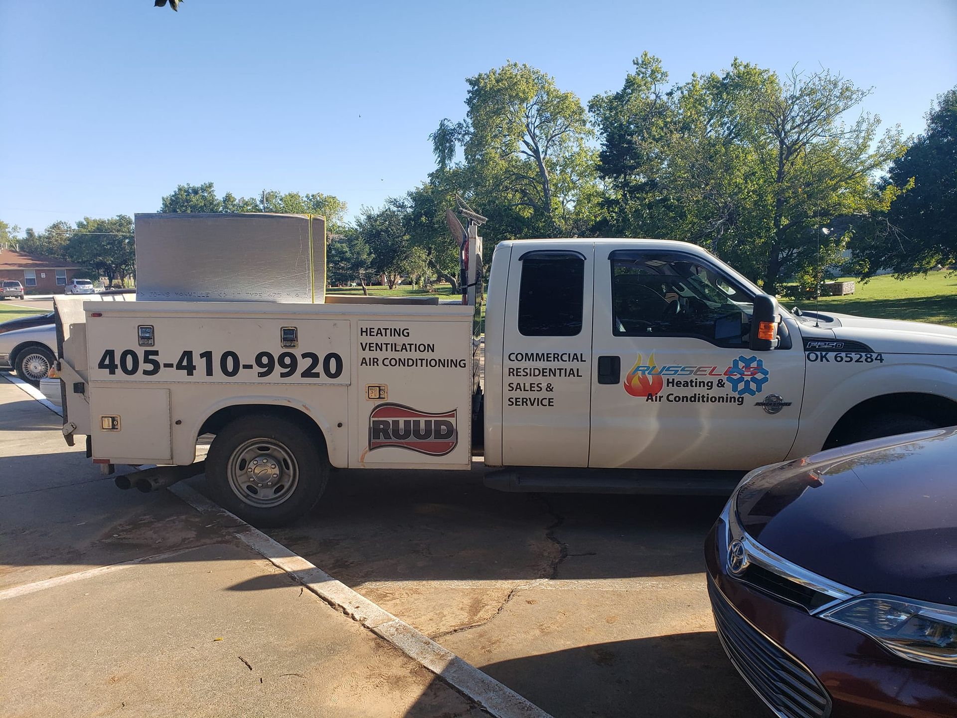 A white truck is parked in a parking lot next to a car.