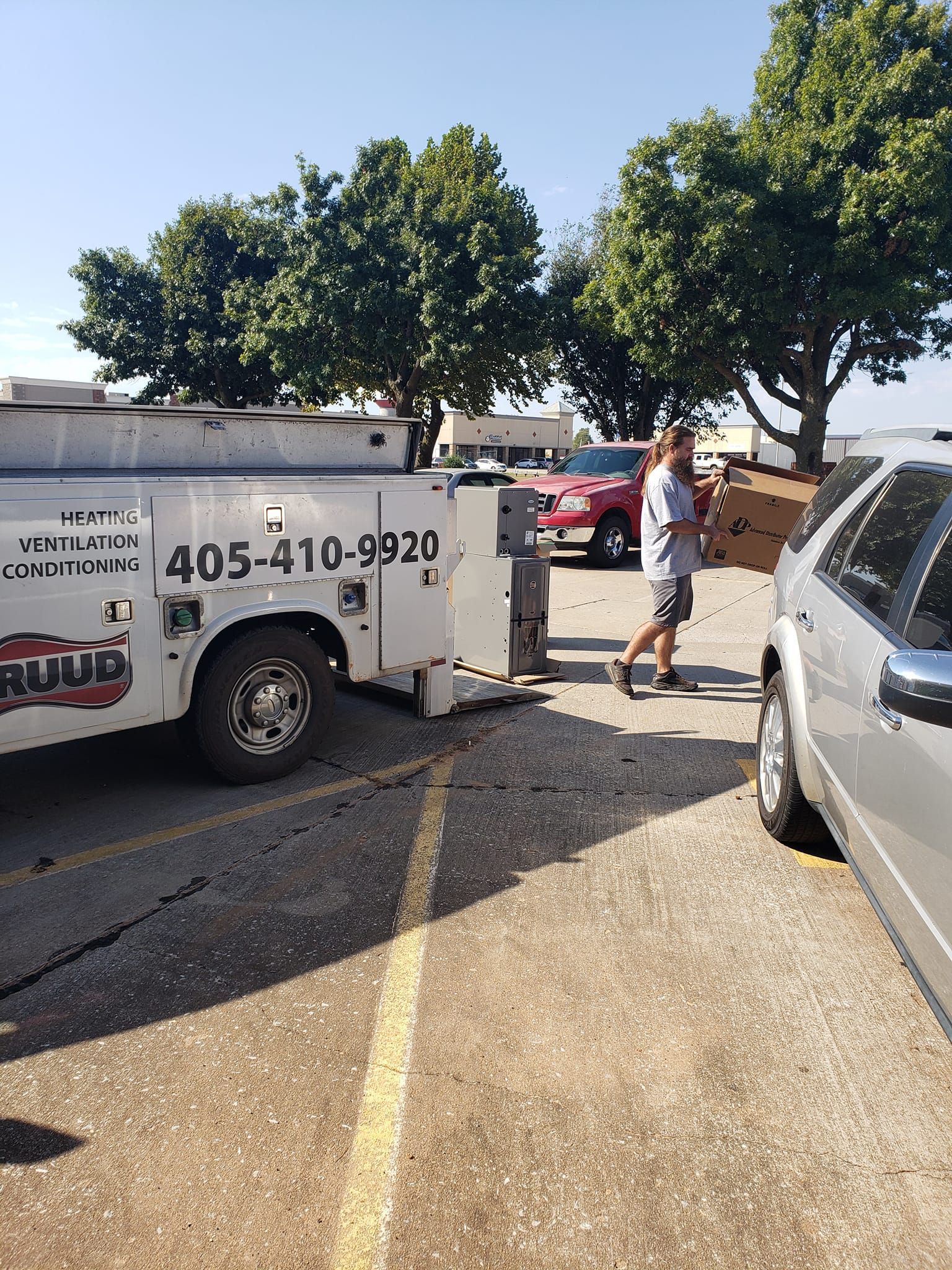 A man is walking towards a tow truck in a parking lot.