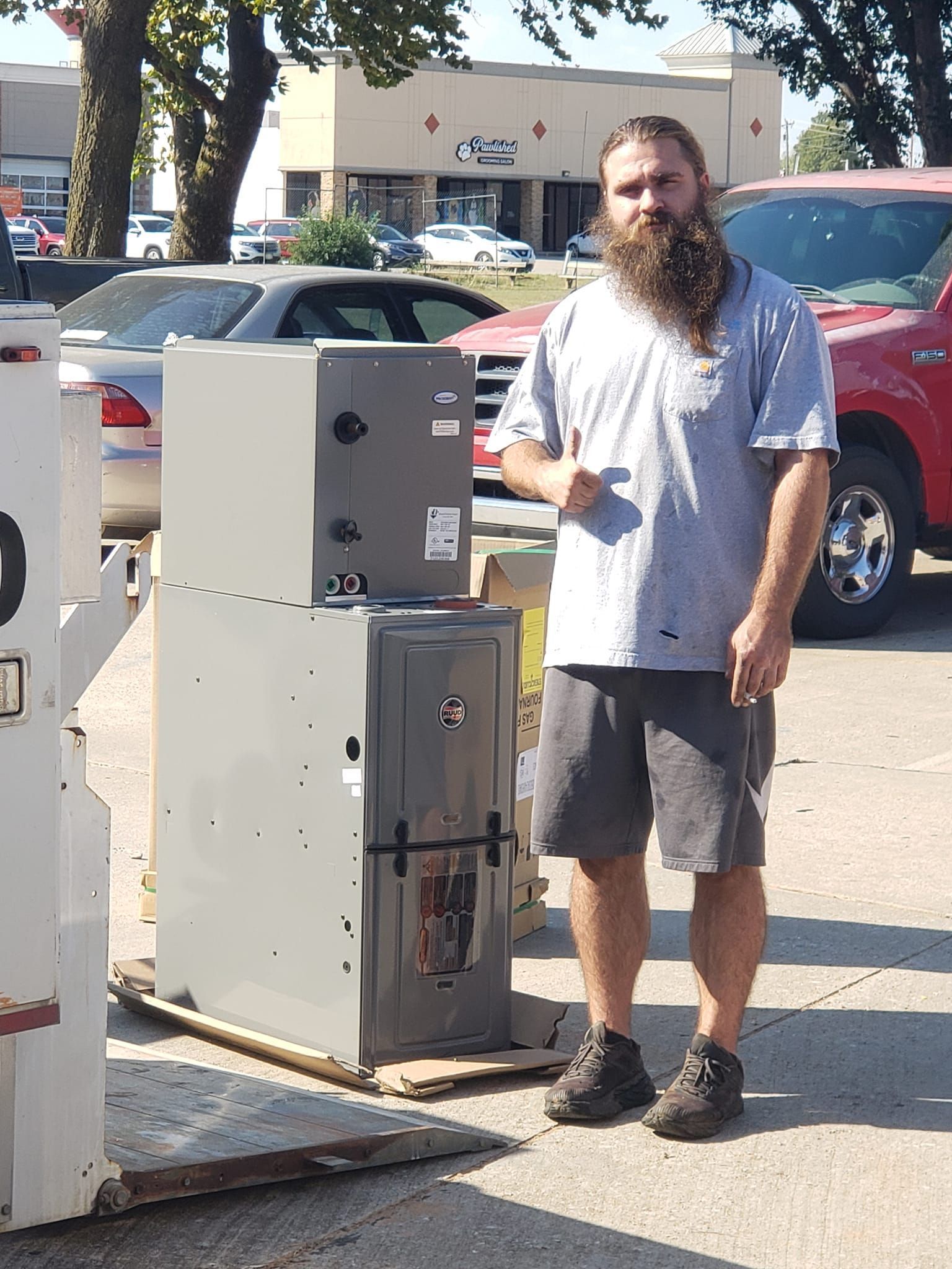 A man with a beard is standing next to a stack of appliances