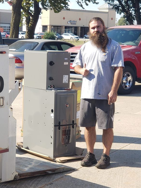 A man with a beard is standing next to a stack of appliances