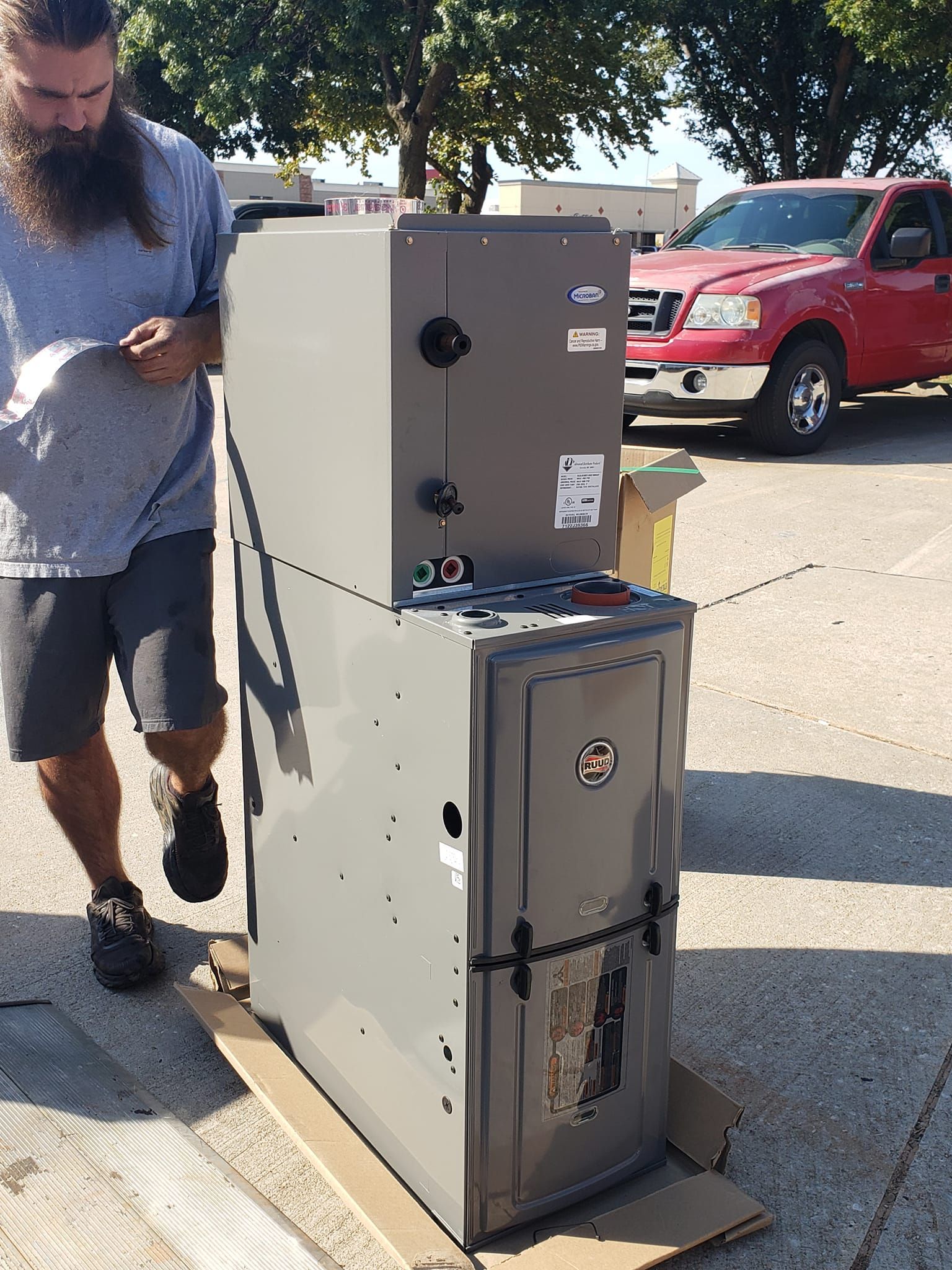 A man with a beard is standing next to an air conditioner
