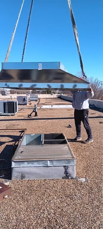 A man is lifting a box on top of a roof with a crane.