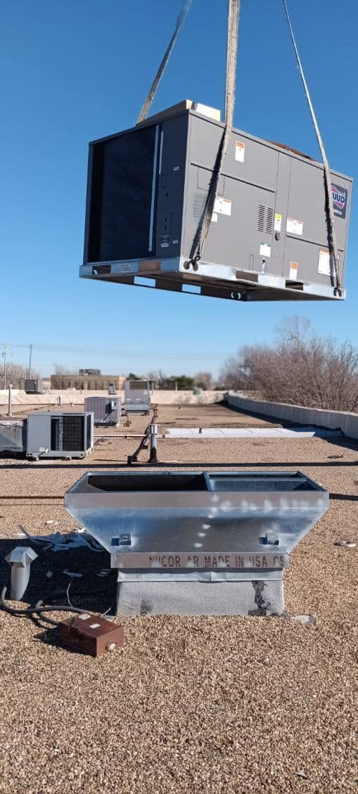 A crane is lifting a box on top of a roof.