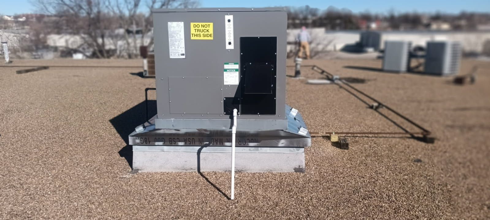An air conditioner is sitting on top of a gravel roof.