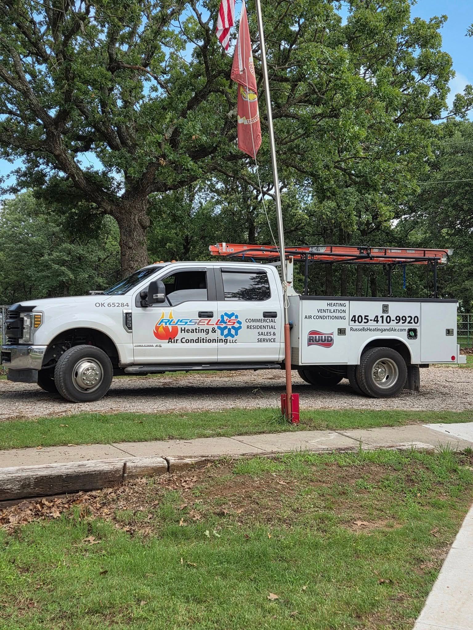 A white truck is parked in front of a flag pole.