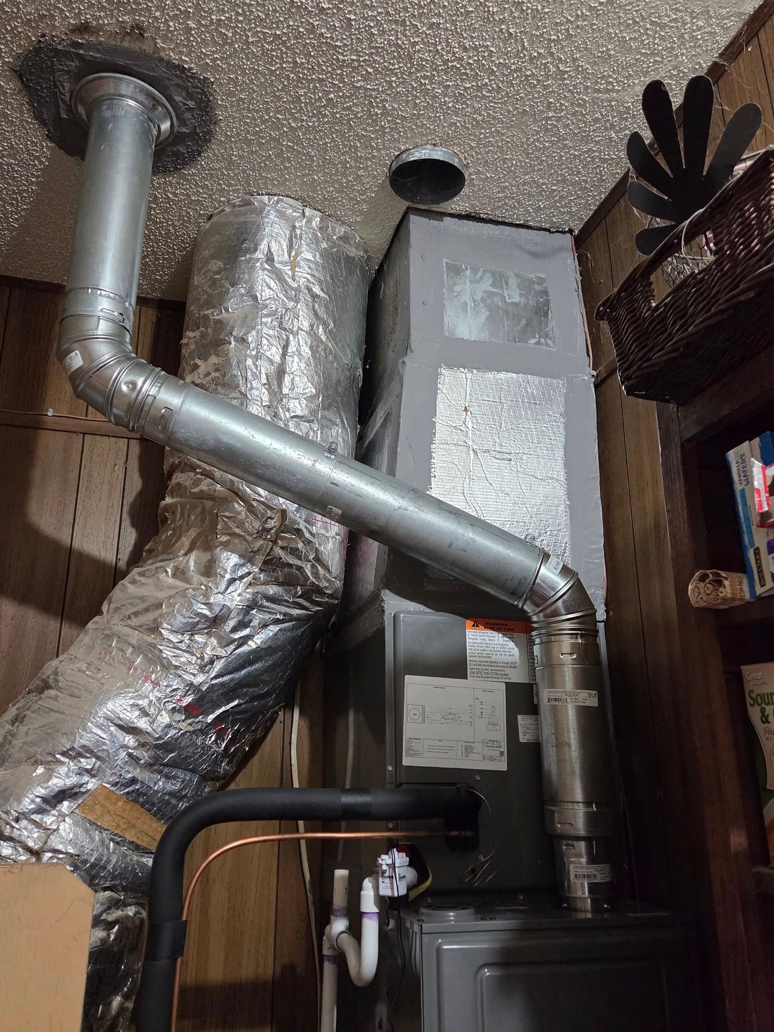 A room with a heater and a pipe coming out of the ceiling.