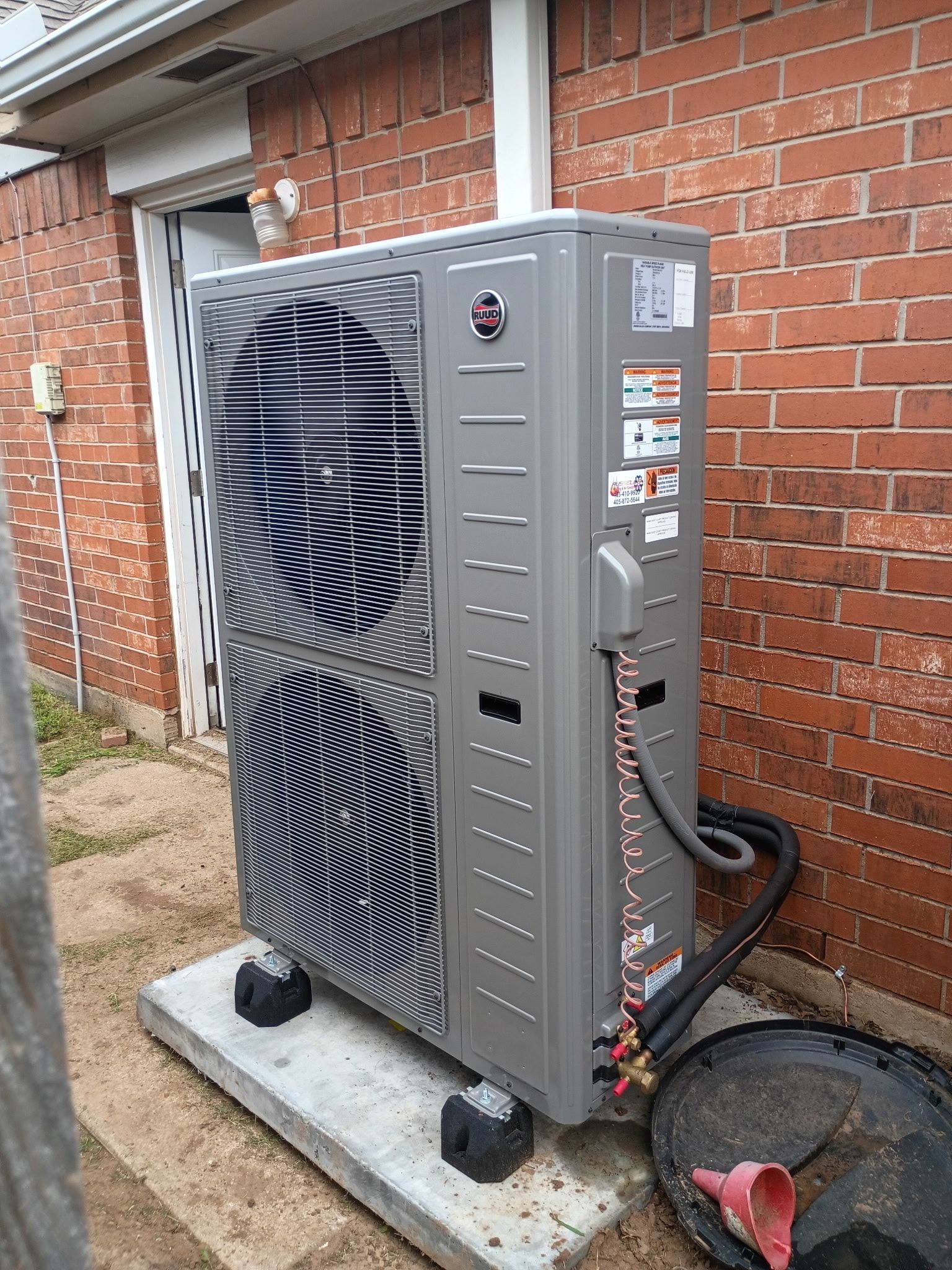 A large air conditioner is sitting outside of a brick building.