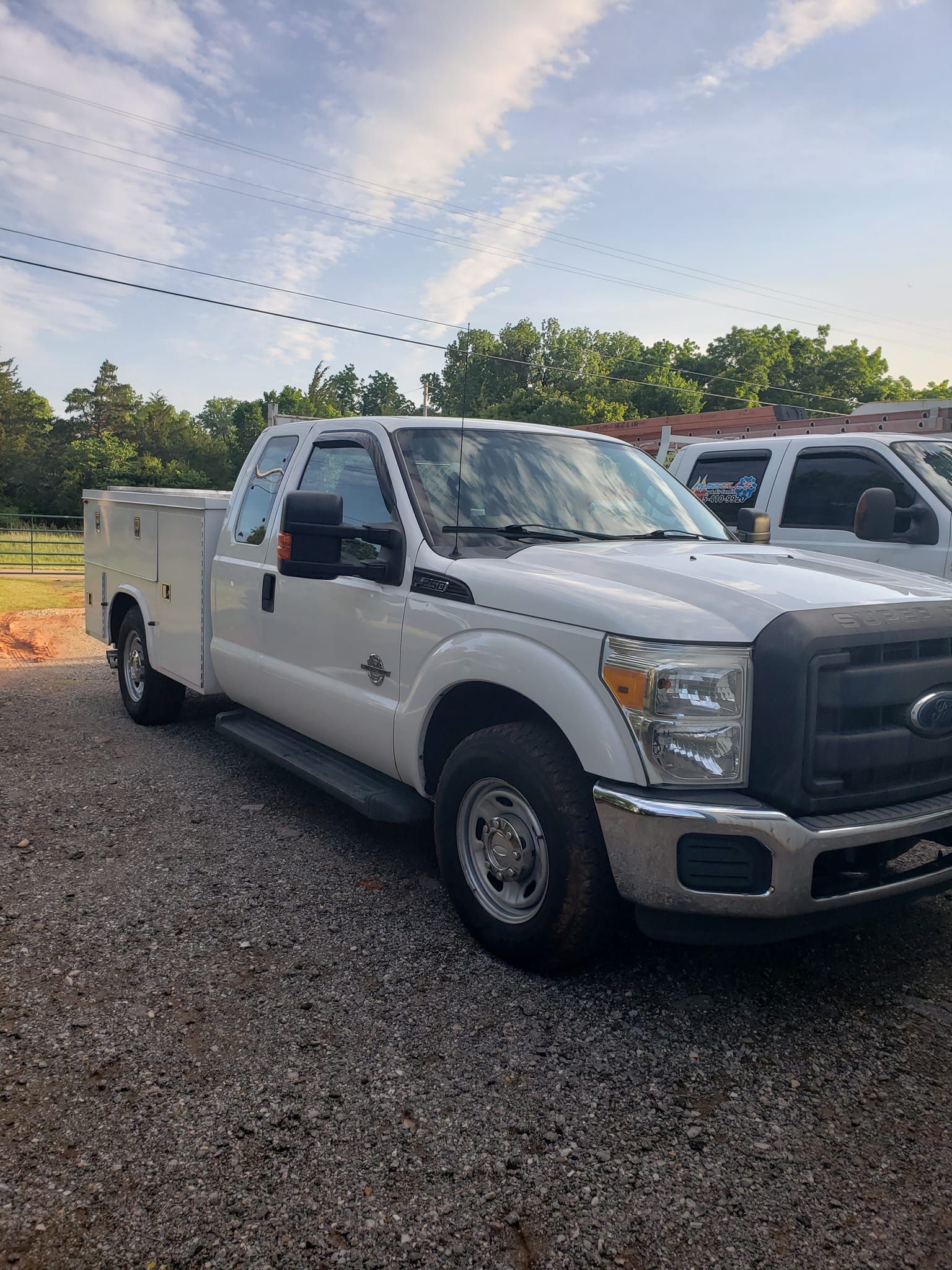 A white utility truck is parked in a gravel lot.