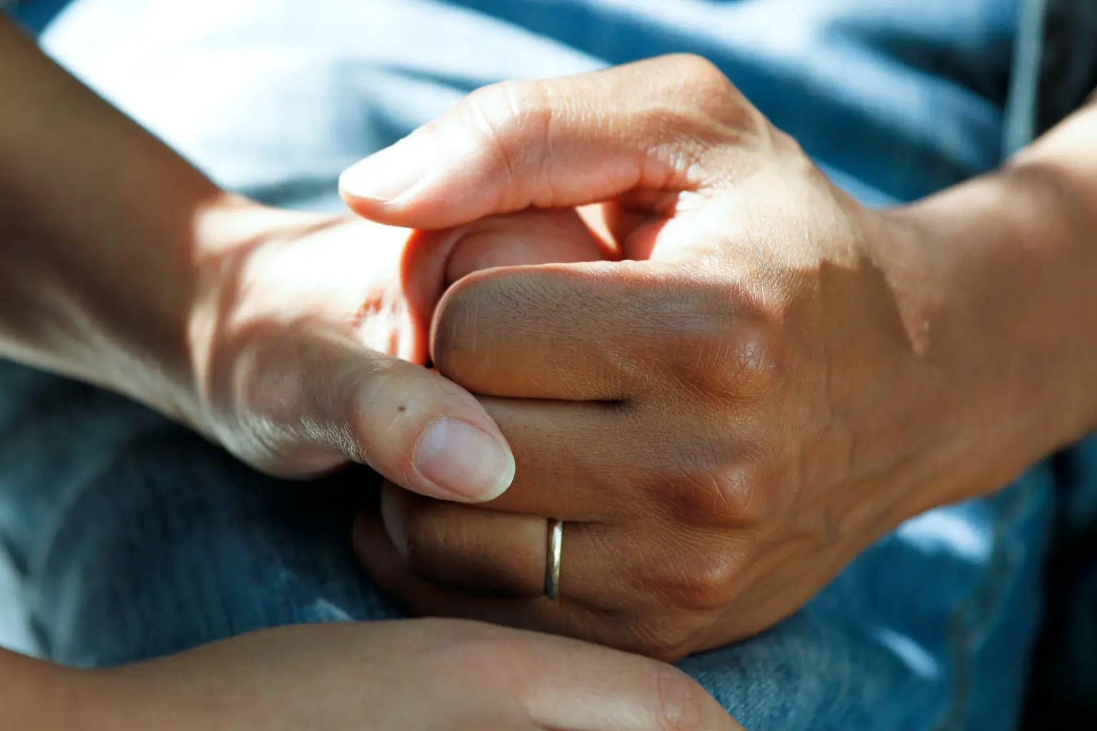 A woman is holding a man 's hand with a wedding ring on her finger.