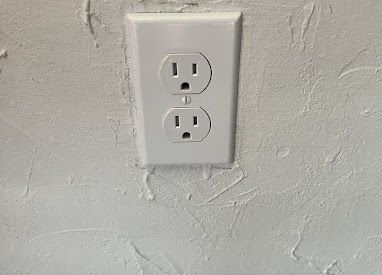 A white electrical outlet on a white wall.
