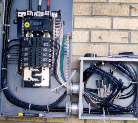 A brick wall with a electrical panel and a box with wires attached to it