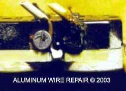 A close up of a broken aluminum wire on a yellow surface.
