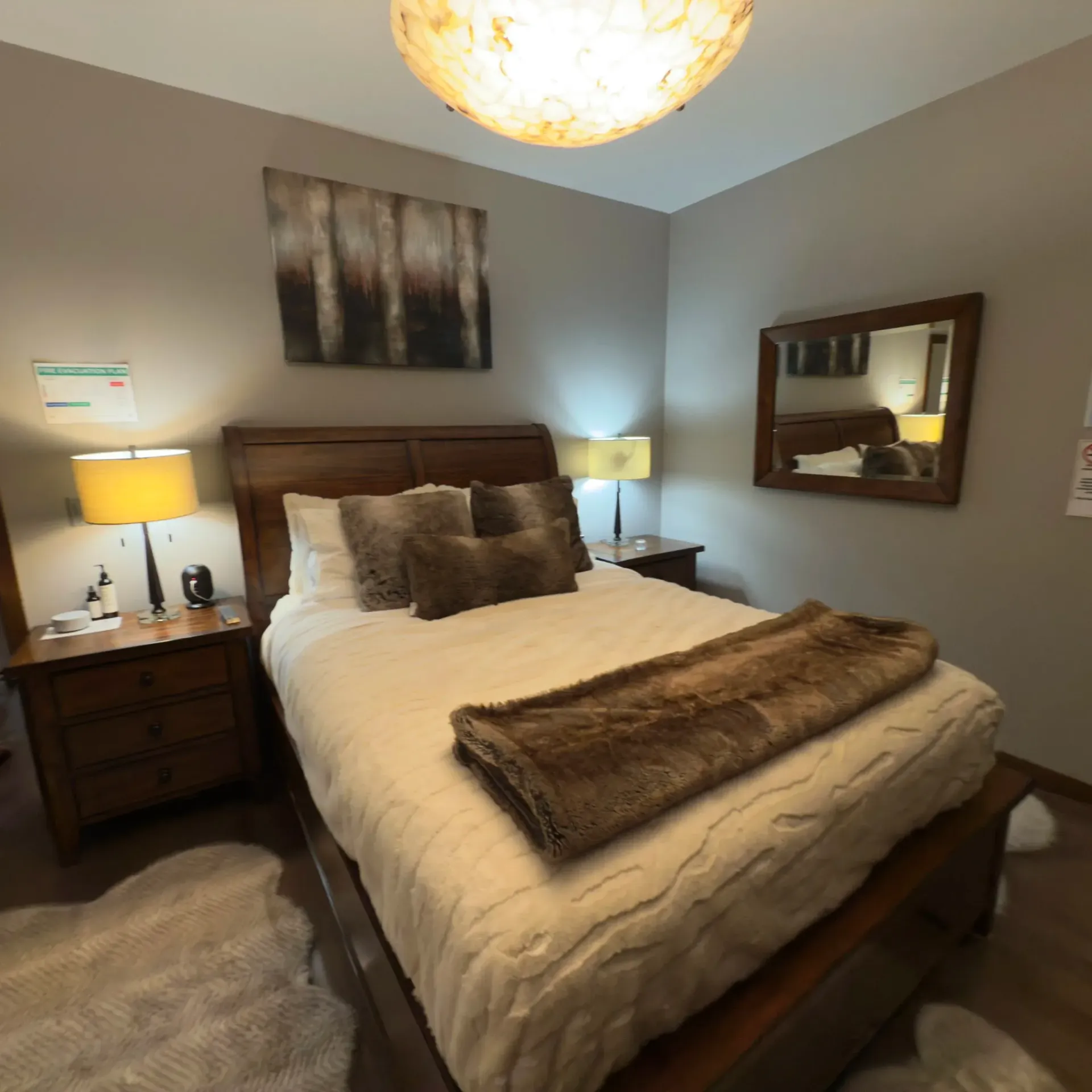 Small bedroom with a white bed, bedside lamps, dark curtains, and a framed painting on the wall.