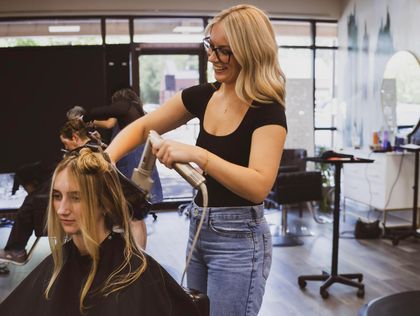 A row of black salon shampoo chairs and white sinks in a bright, modern hair salon.