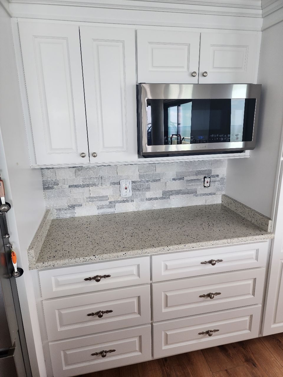 White kitchen cabinets with granite countertop and stainless steel microwave above drawers