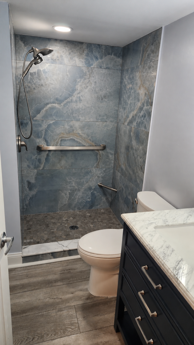 Small beige bathroom with a white vanity, mirror, toilet, and bathtub/shower combo.