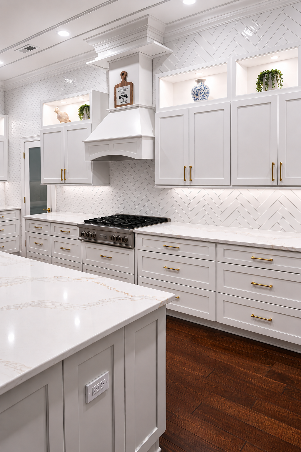 Bright white kitchen with marble counters, gold hardware, built-in cabinets, and dark wood floors
