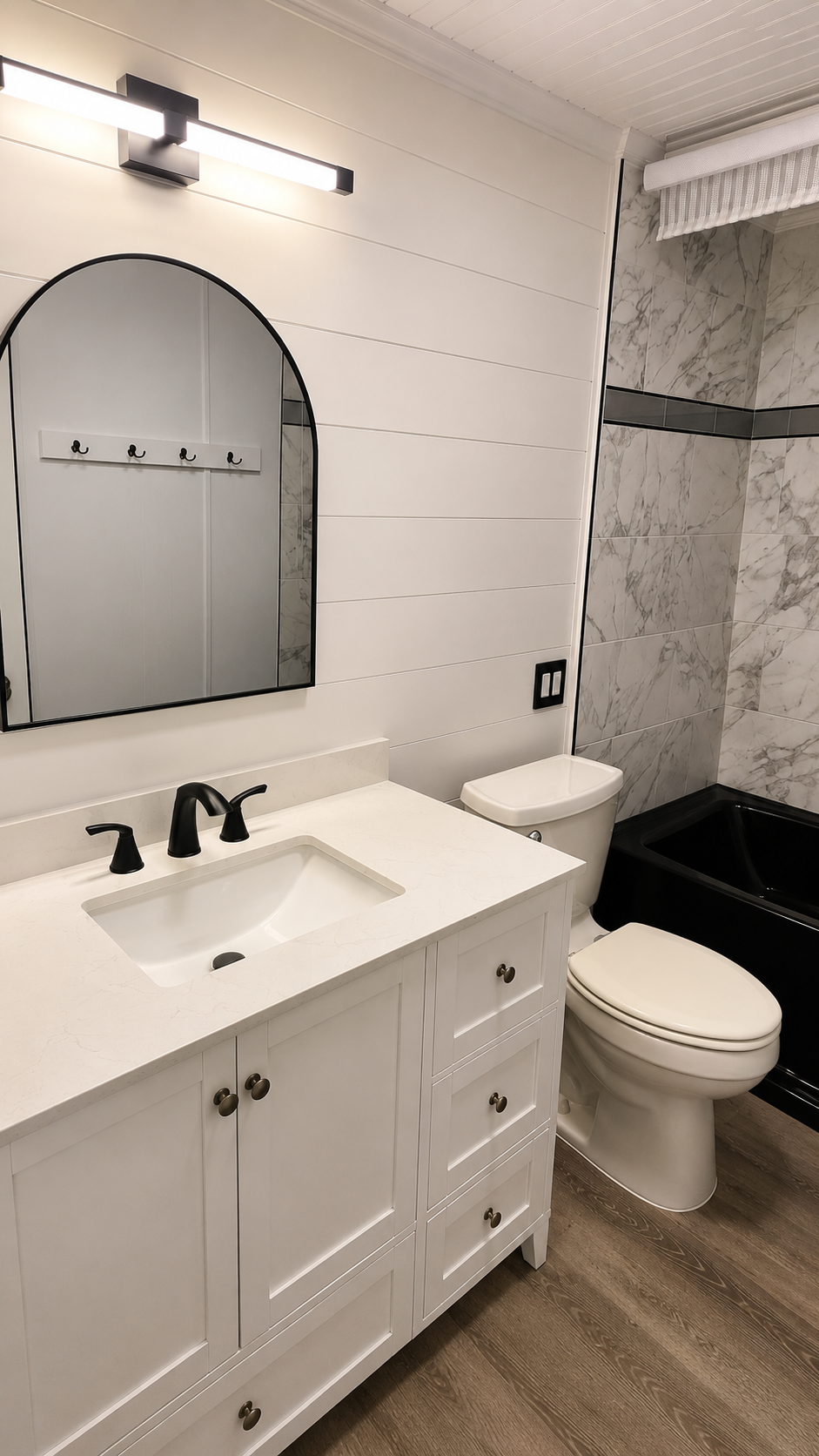 Modern bathroom with white vanity, mirror, toilet, and marble shower tile.