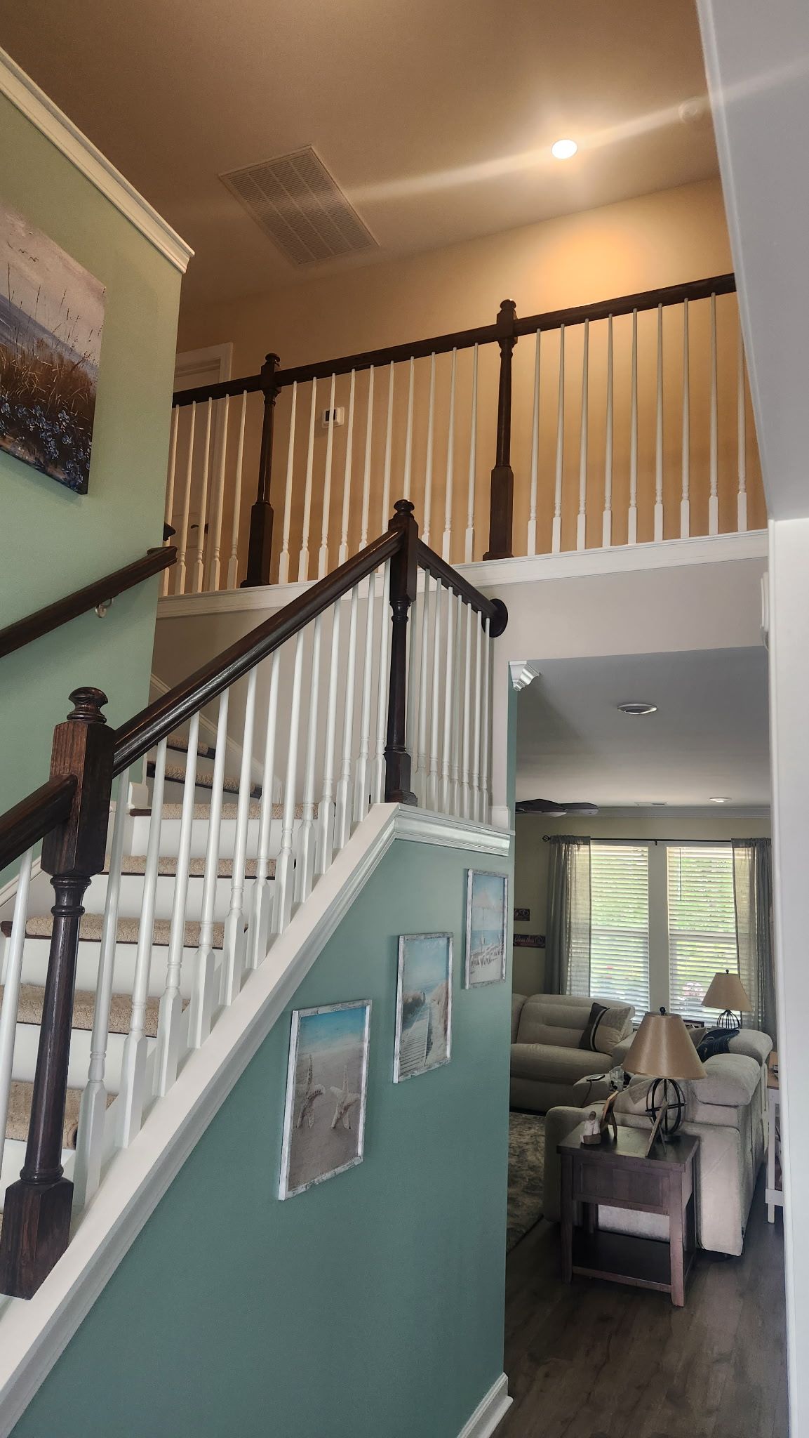 Two-story home interior with staircase, balcony railing, and a dining area below
