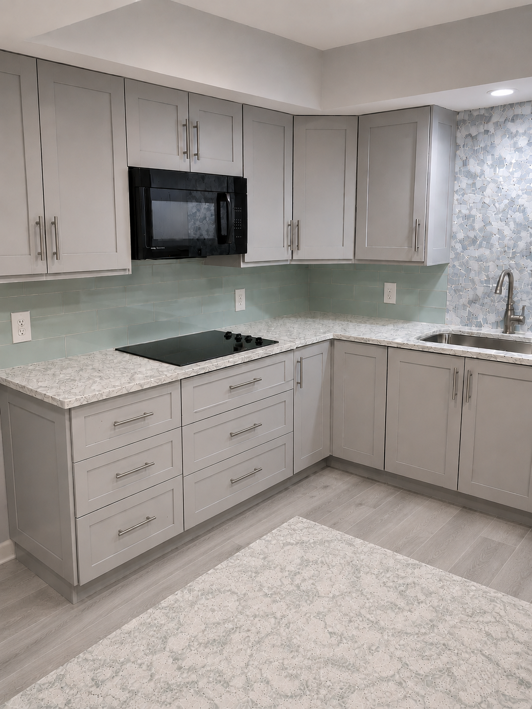 Modern kitchen with light gray cabinets, white countertops, black cooktop, and mosaic backsplash