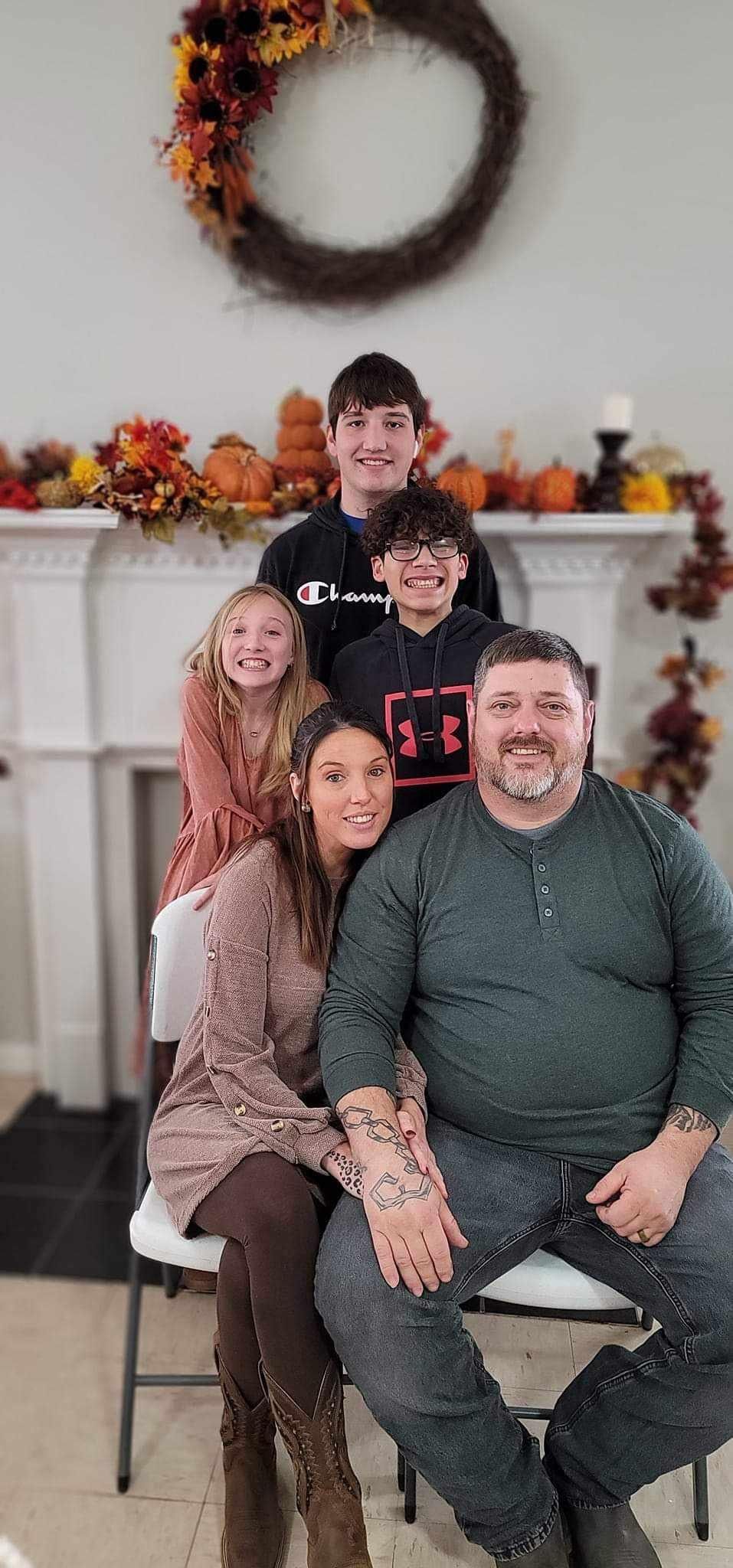 A family is posing for a picture in front of a fireplace.