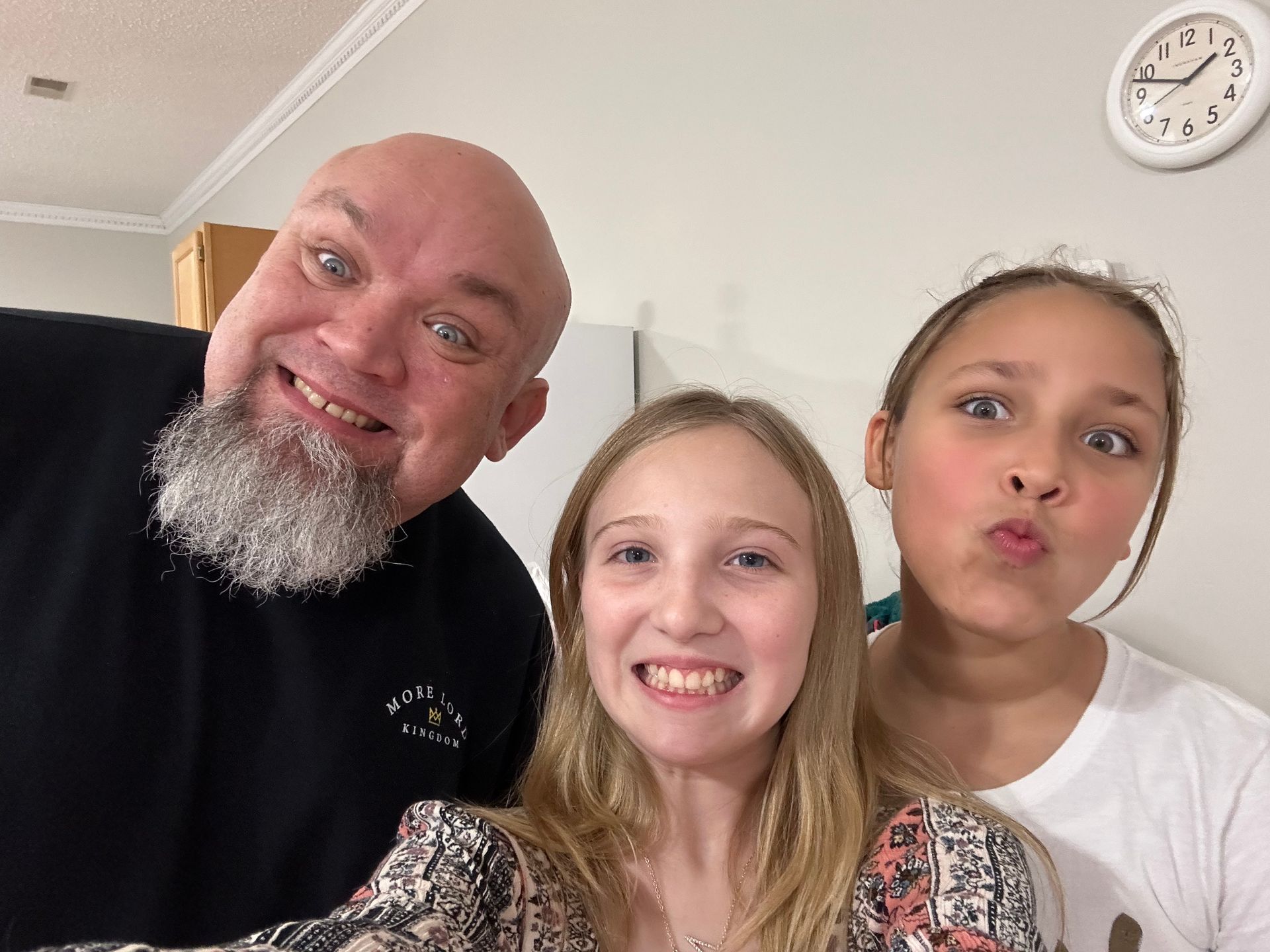 A man with a beard is posing for a picture with two girls.