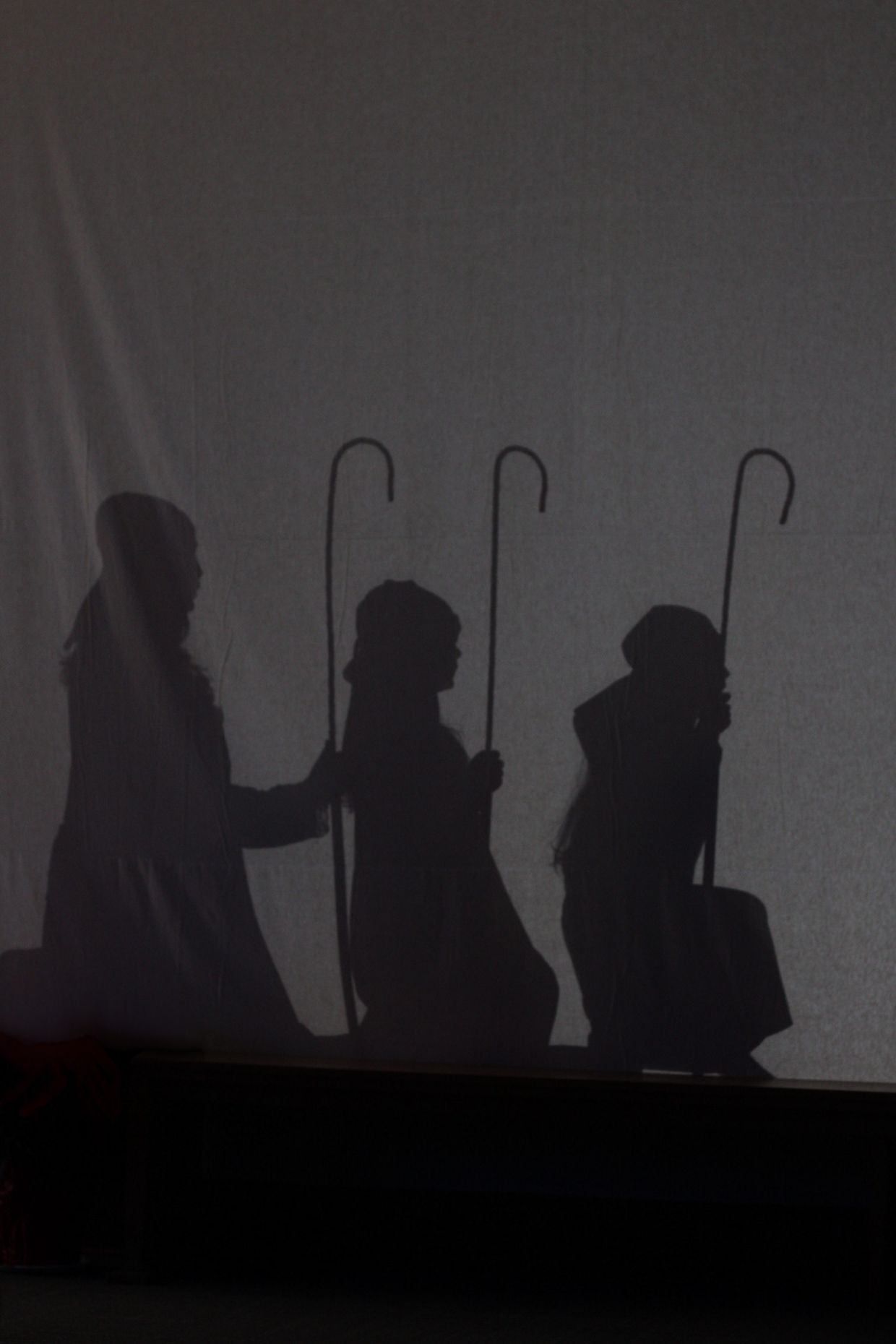 A group of people standing next to each other holding canes in a dark room.
