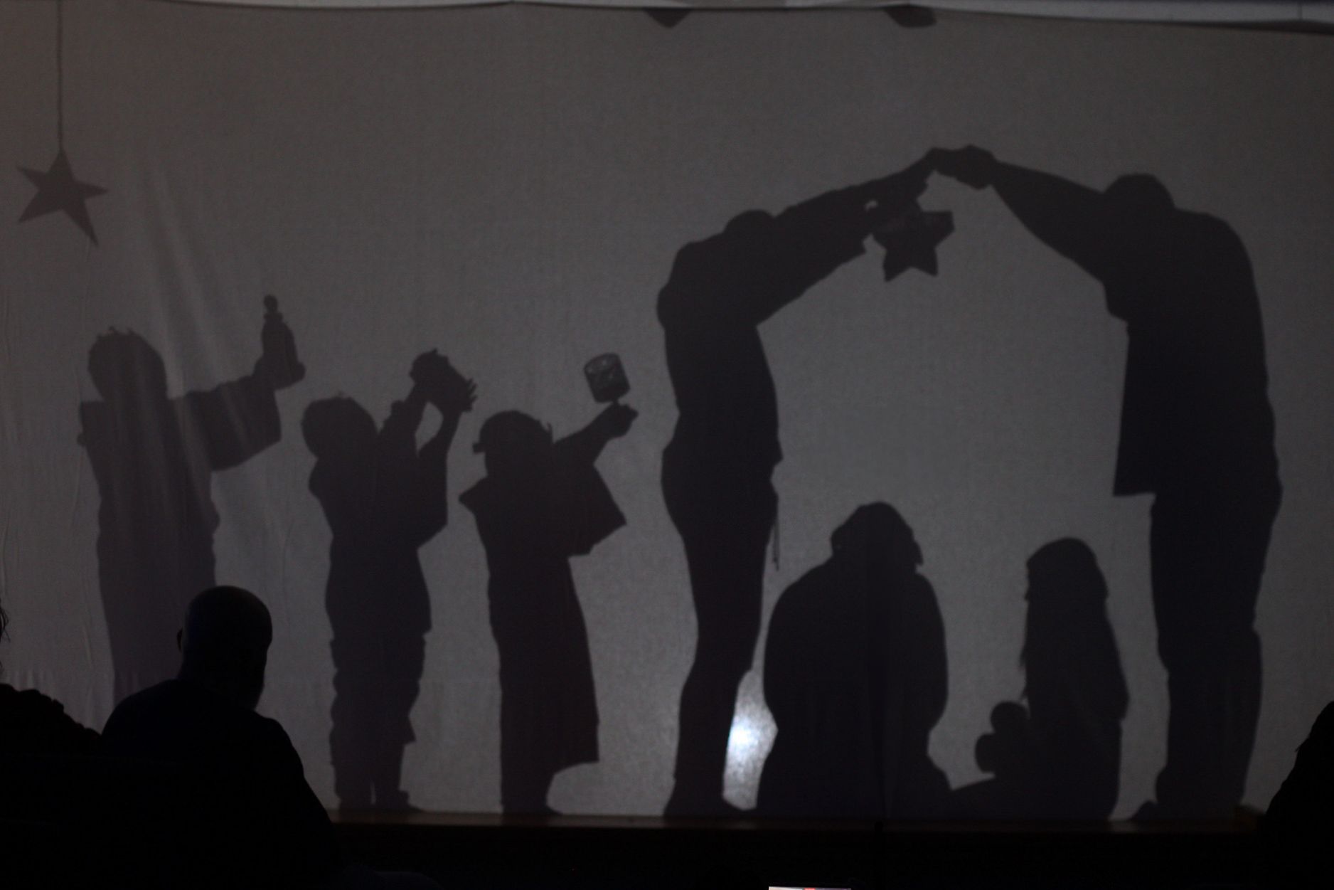 The shadows of a nativity scene are projected on a wall.