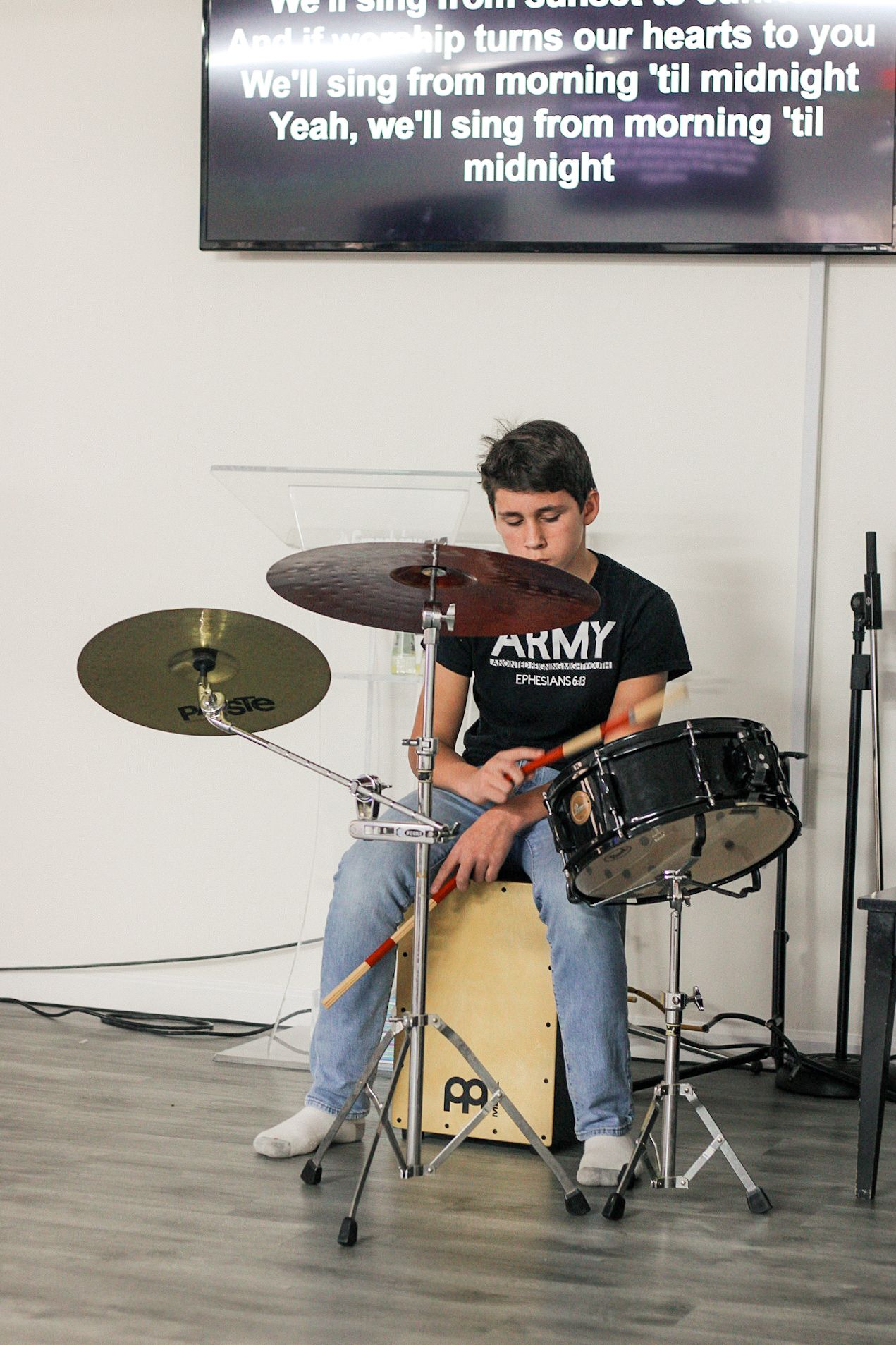 A young man is playing drums while sitting on a drum set.