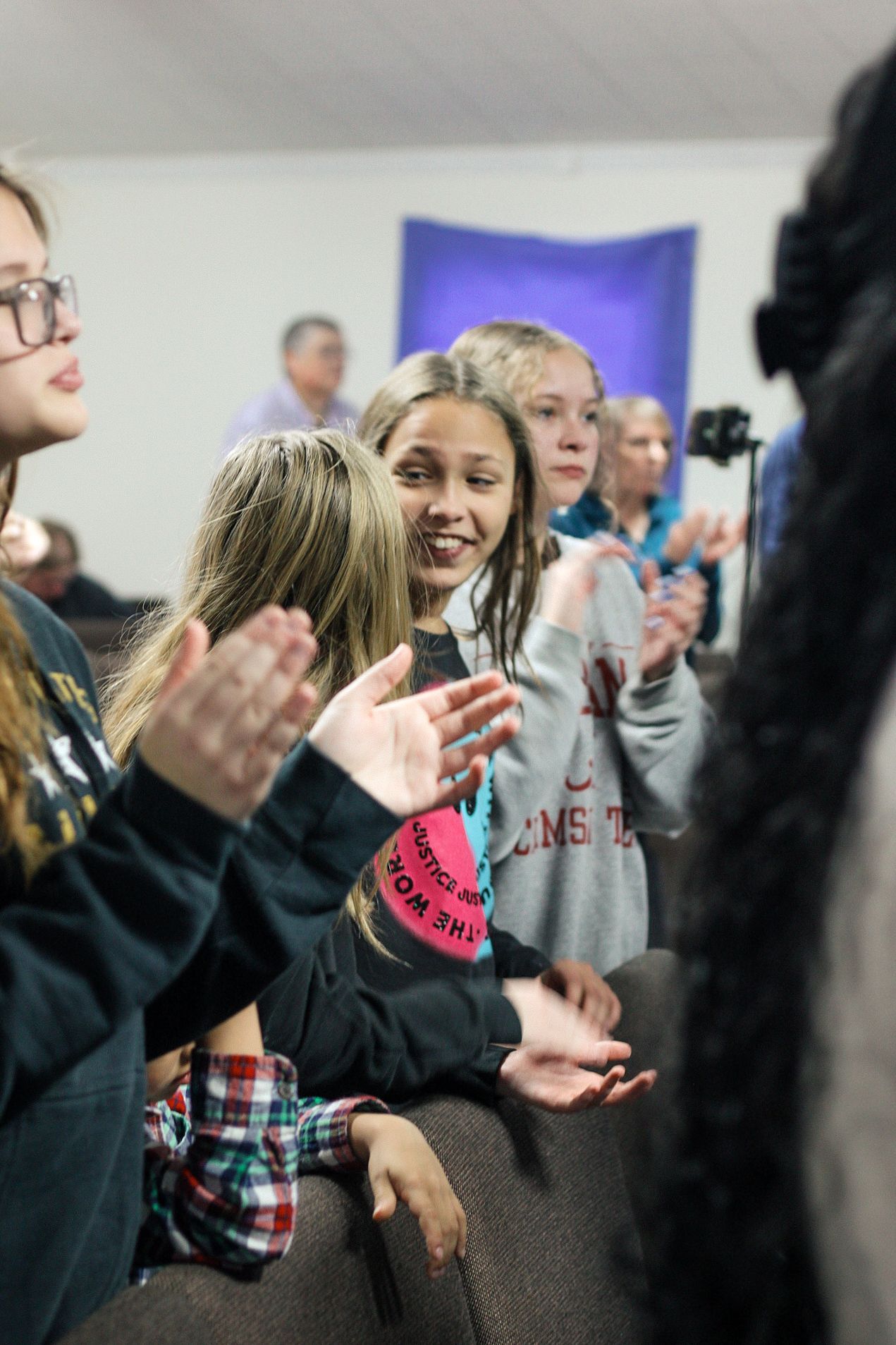 A group of young girls are clapping their hands in a church.