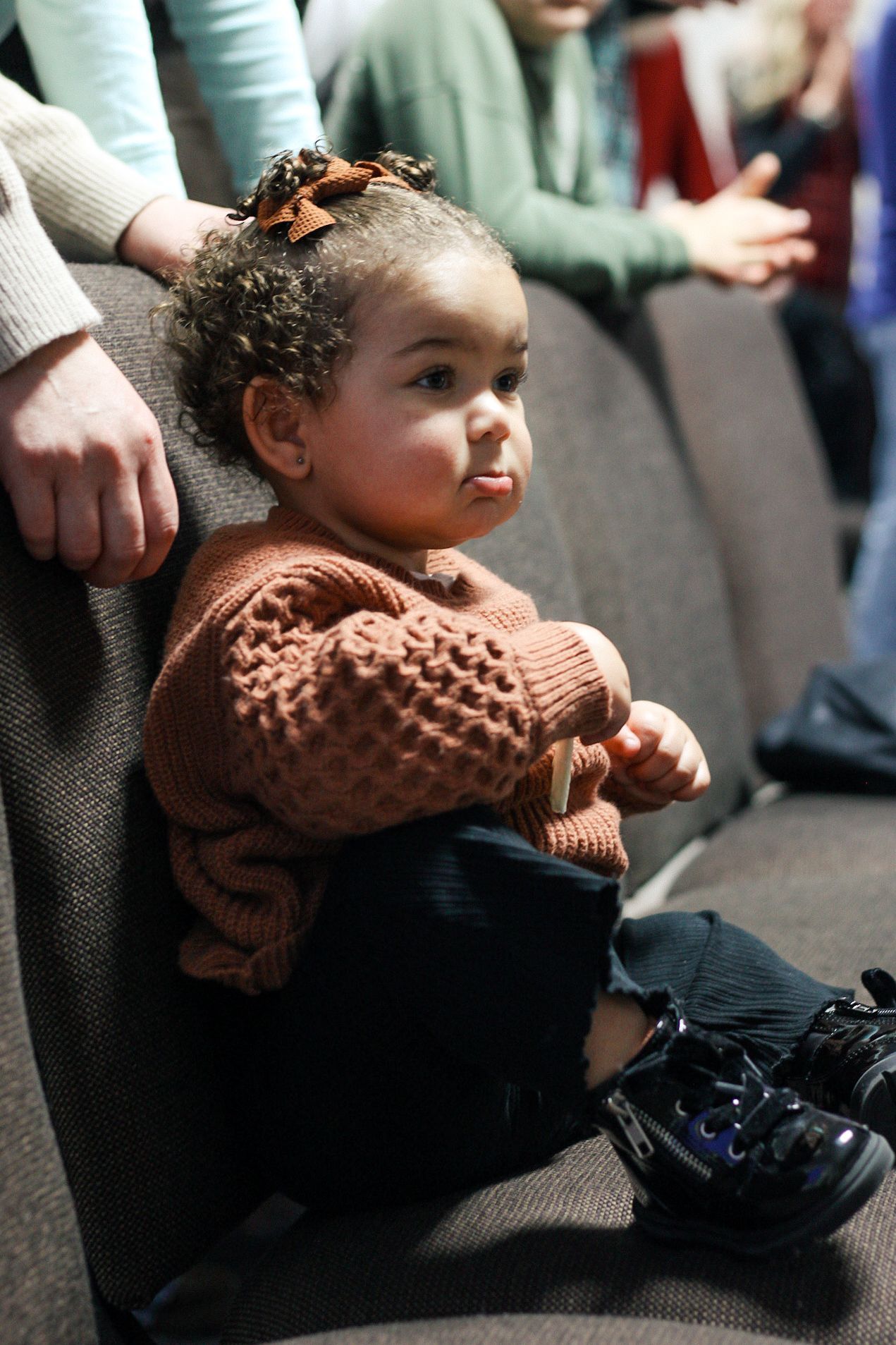 A little girl is sitting on a couch looking at something.