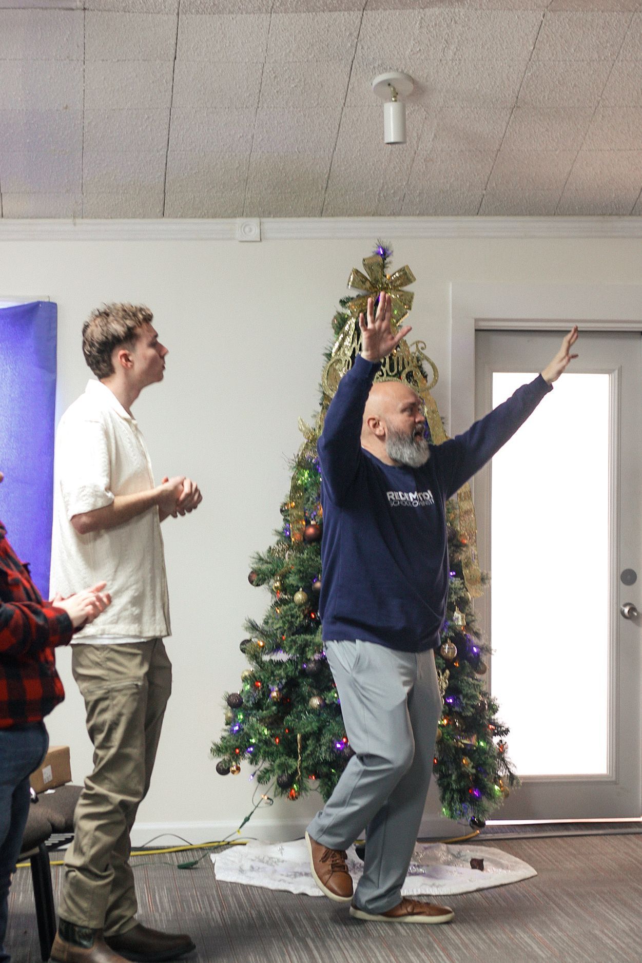 A man is dancing in front of a christmas tree