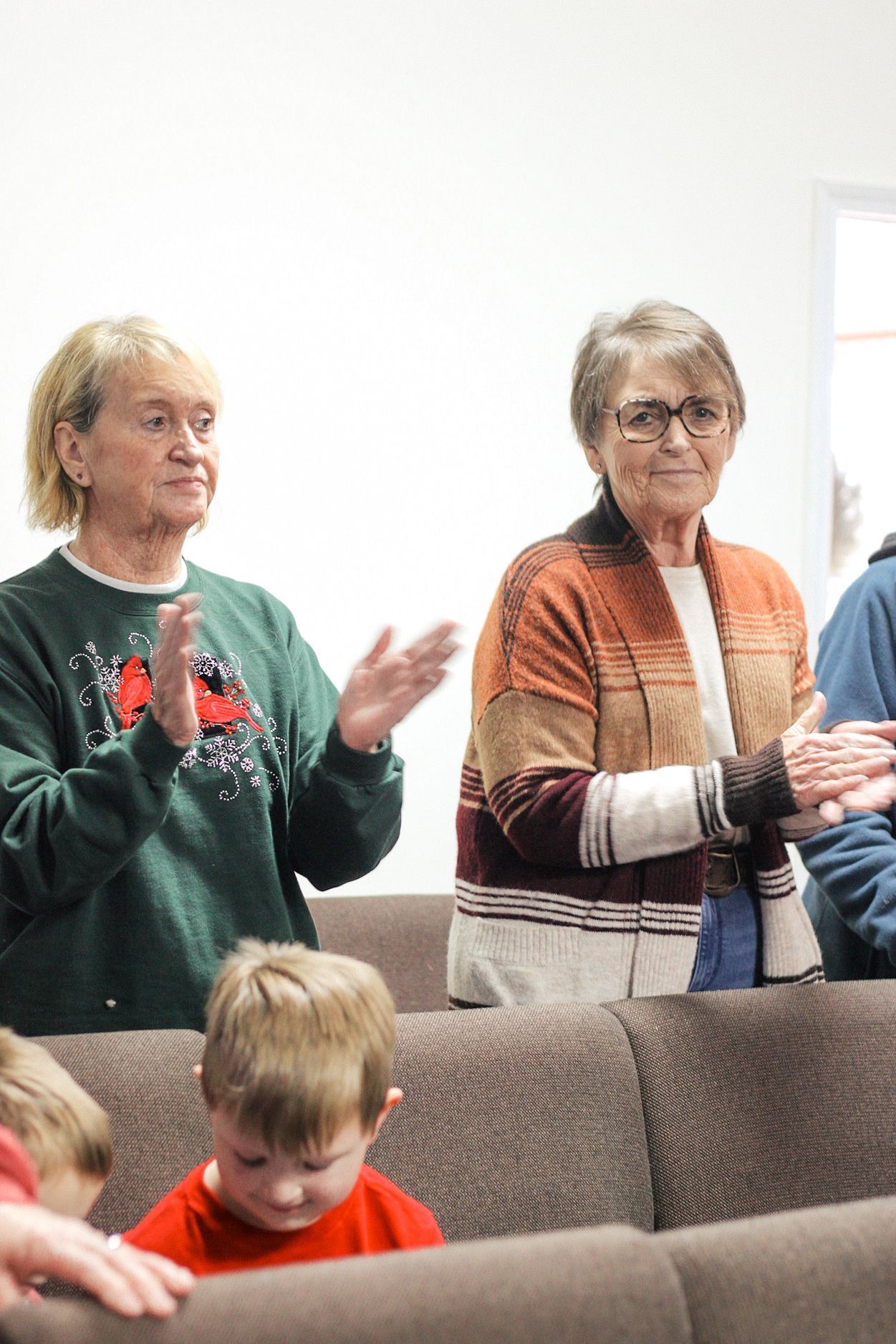 A group of people are sitting on a couch clapping their hands.